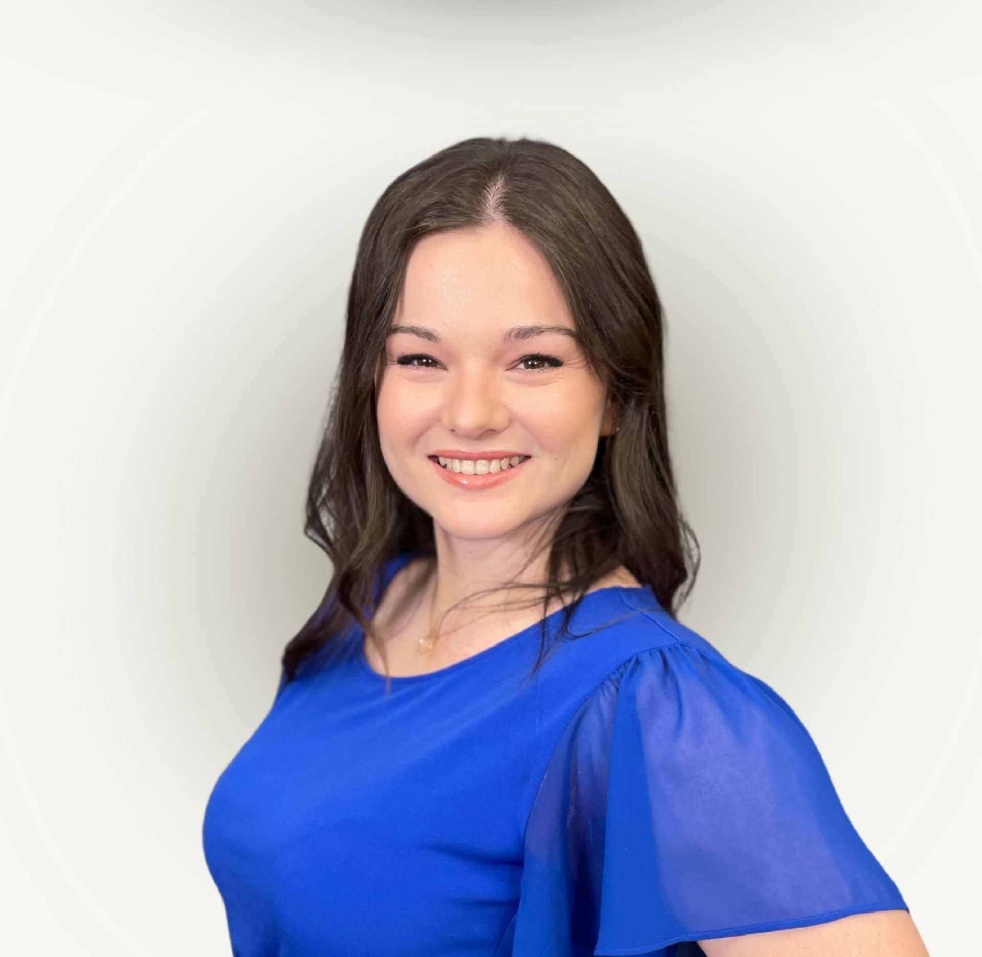 A woman in a blue shirt is smiling for the camera.