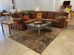 A living room with a brown sectional couch and a coffee table.