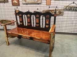 A wooden bench is sitting in front of a wall with signs on it.