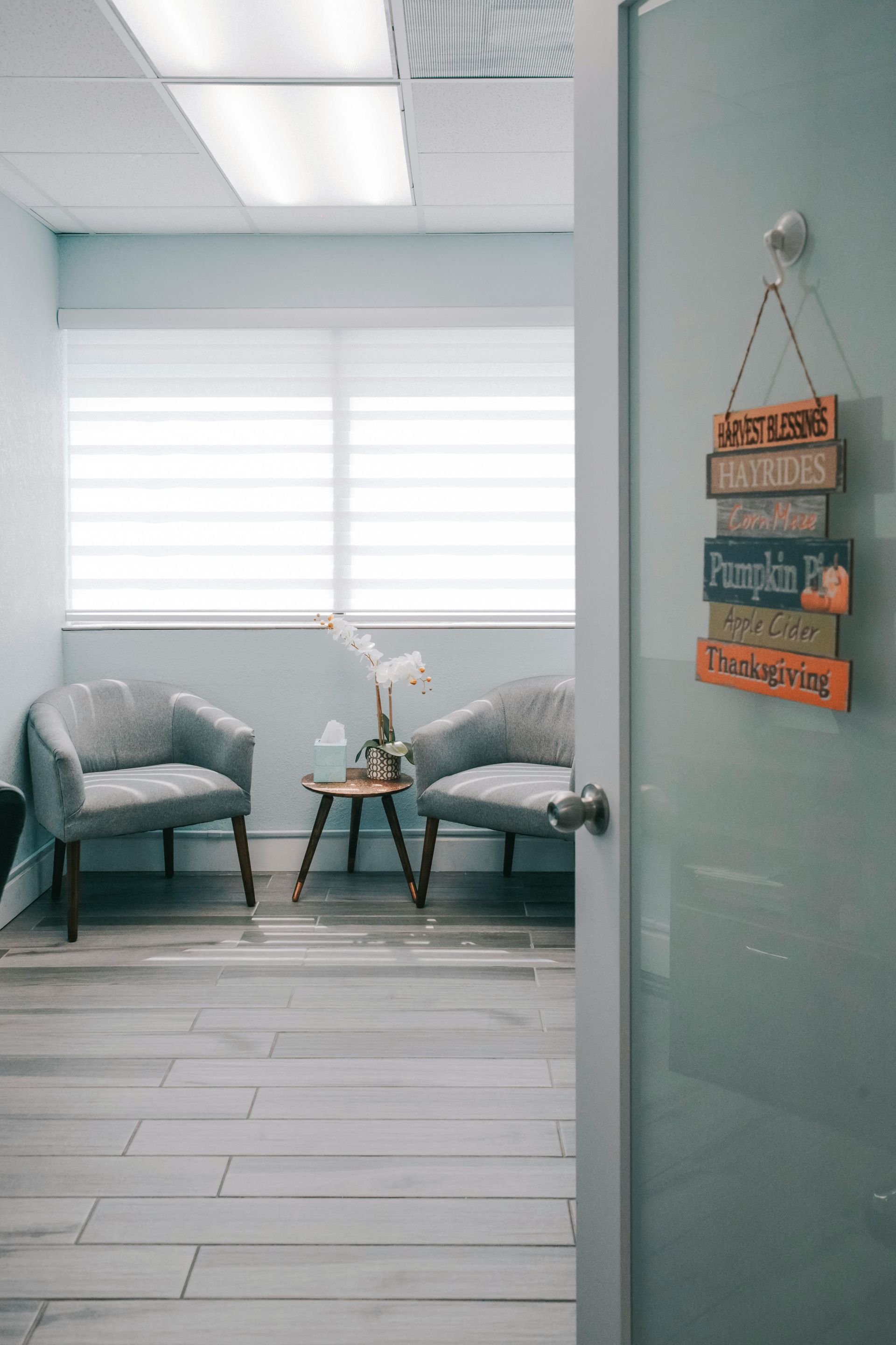 A waiting room with two chairs and a sign hanging on the door.