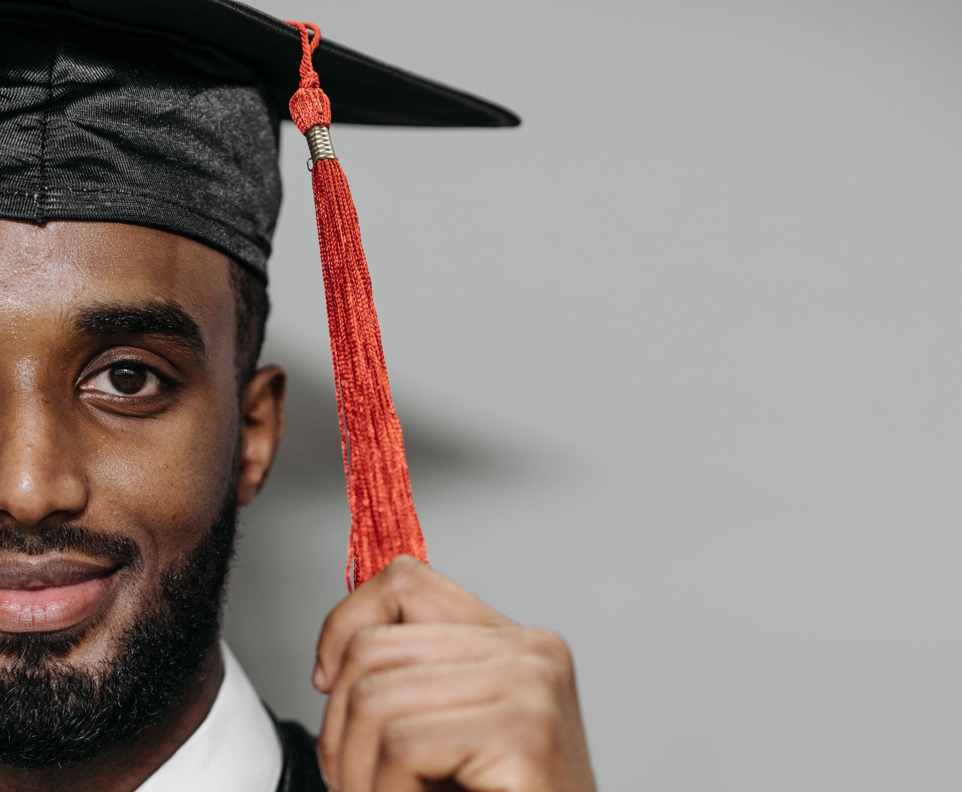 School graduate holding red tassle.