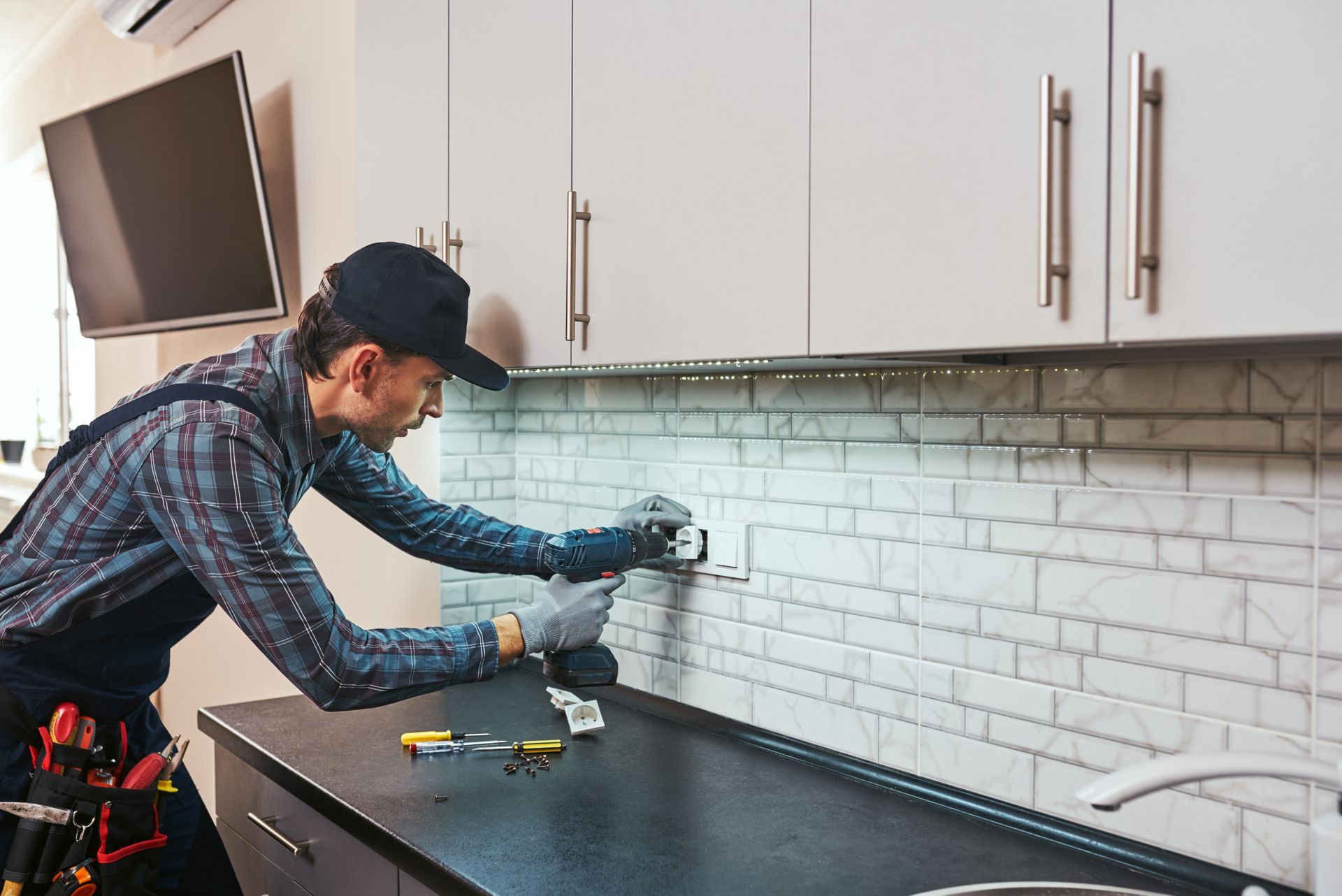 A man is installing a socket in a kitchen.