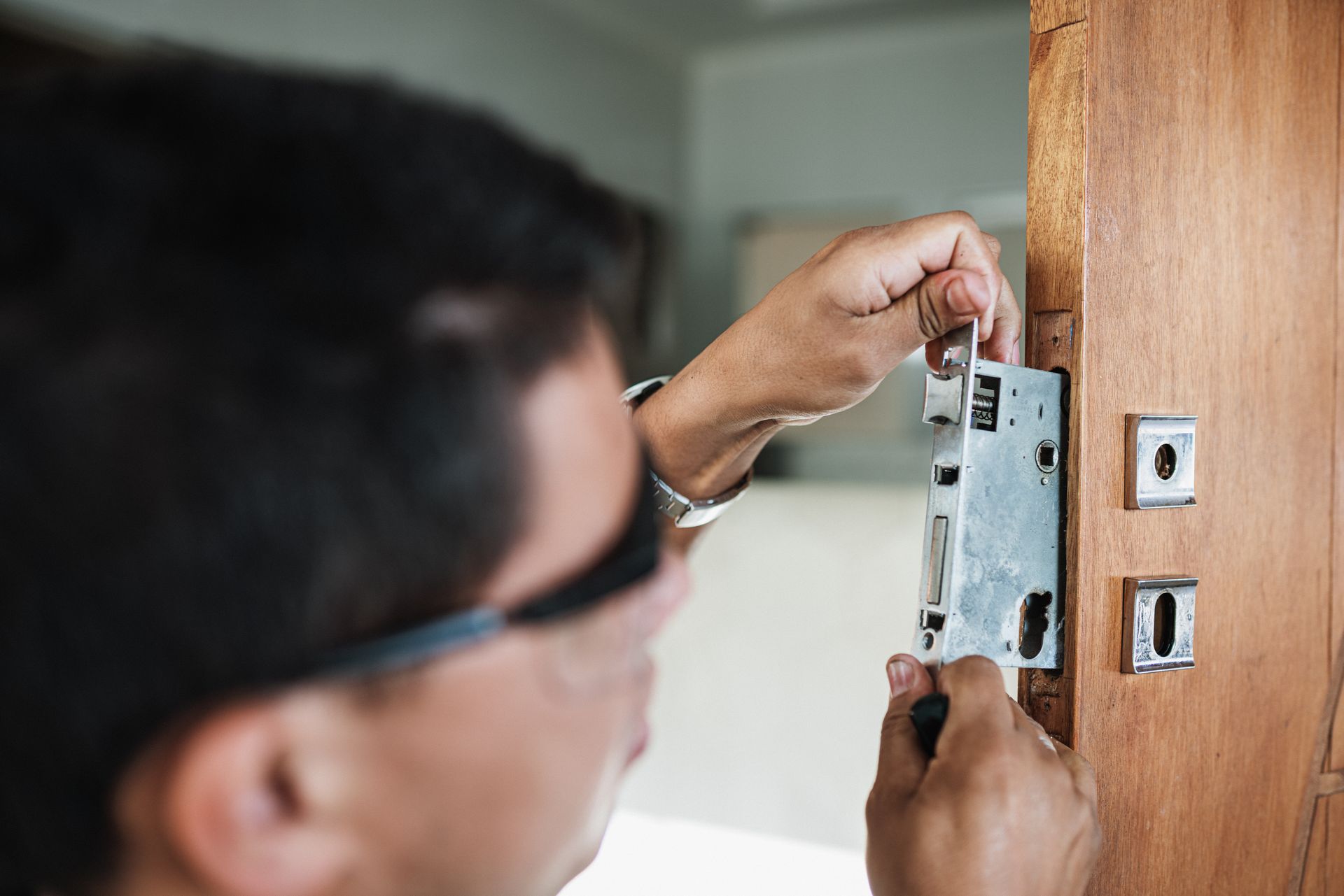 A man is measuring a cabinet with a tape measure in a kitchen.