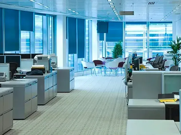 Modern open-plan office with cubicles, desks, computers, and large windows