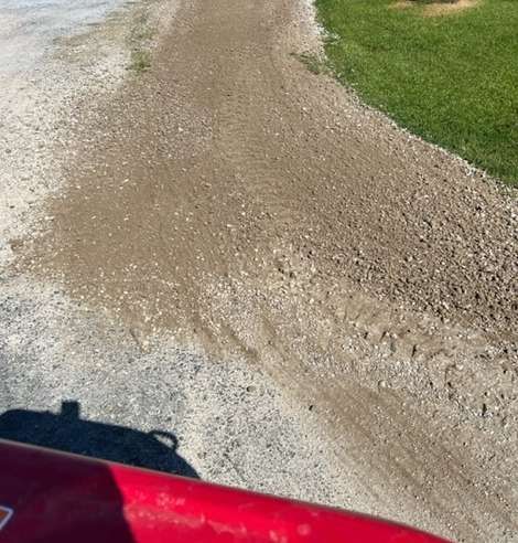 A red truck is parked on the side of a dirt road.