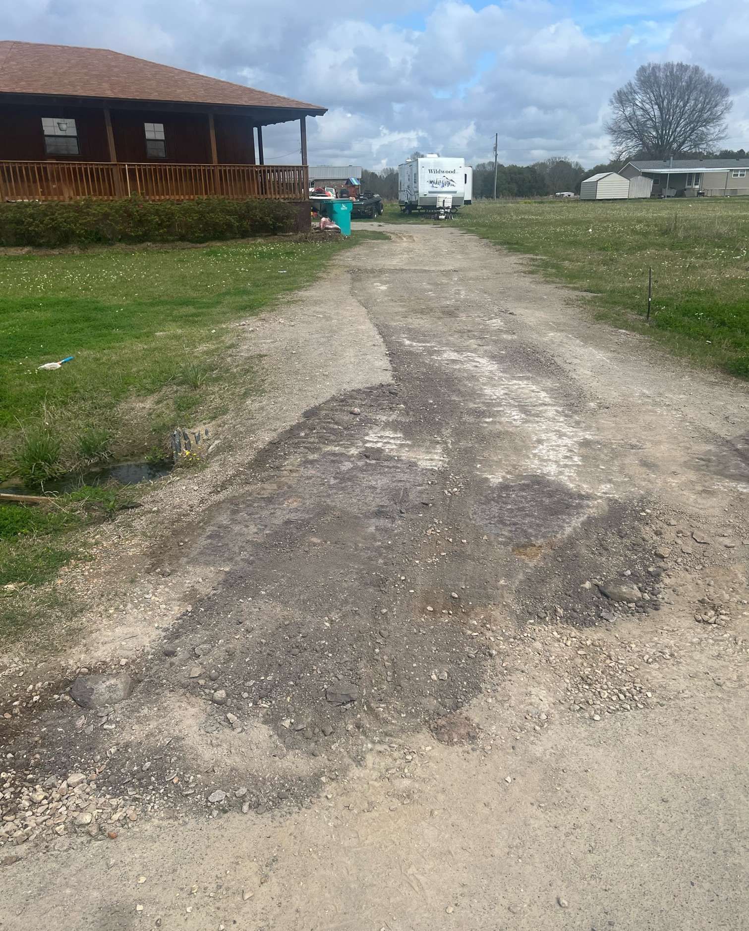 A dirt road leading to a house with a porch.