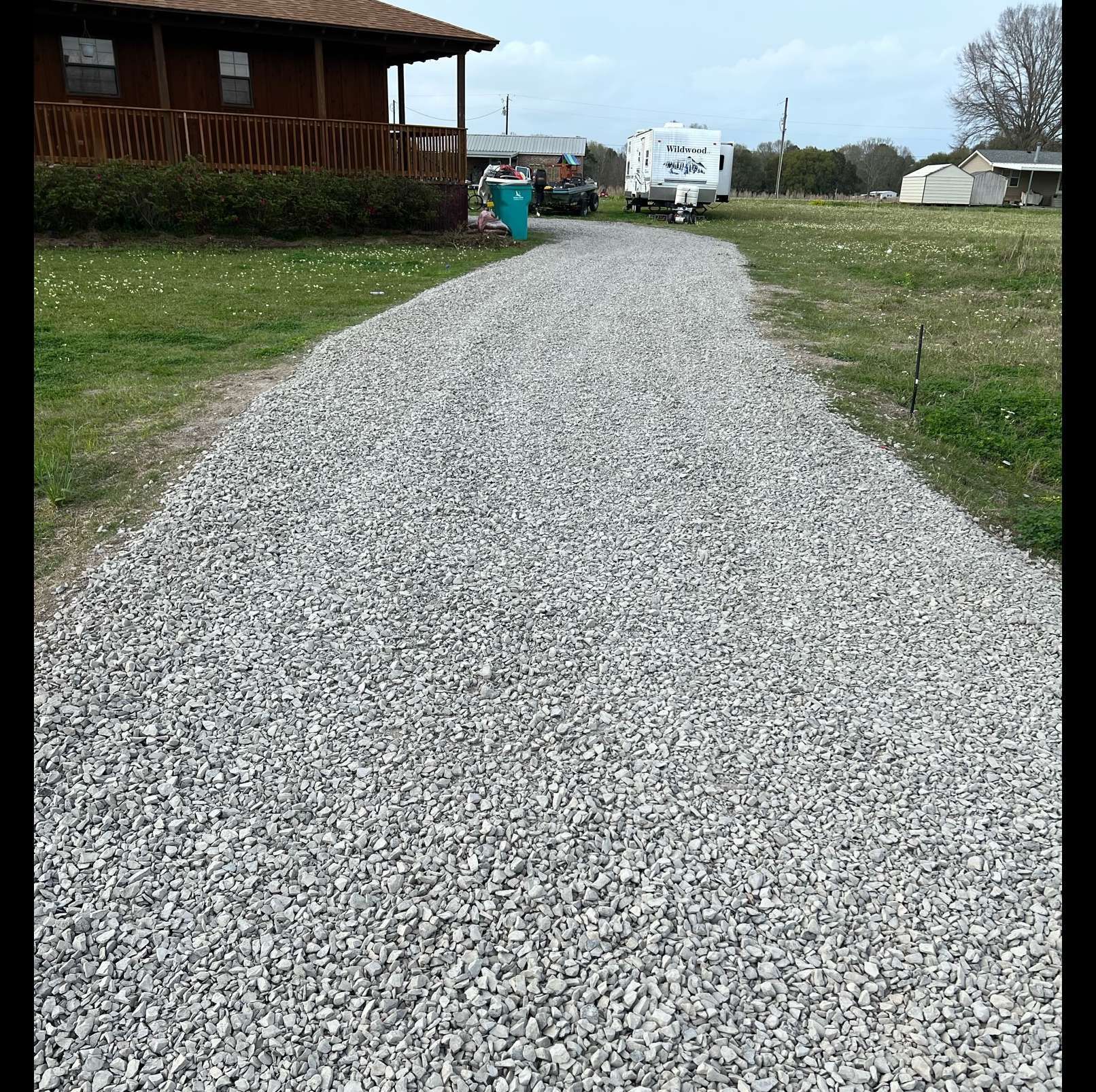A gravel driveway leading to a house and a trailer.