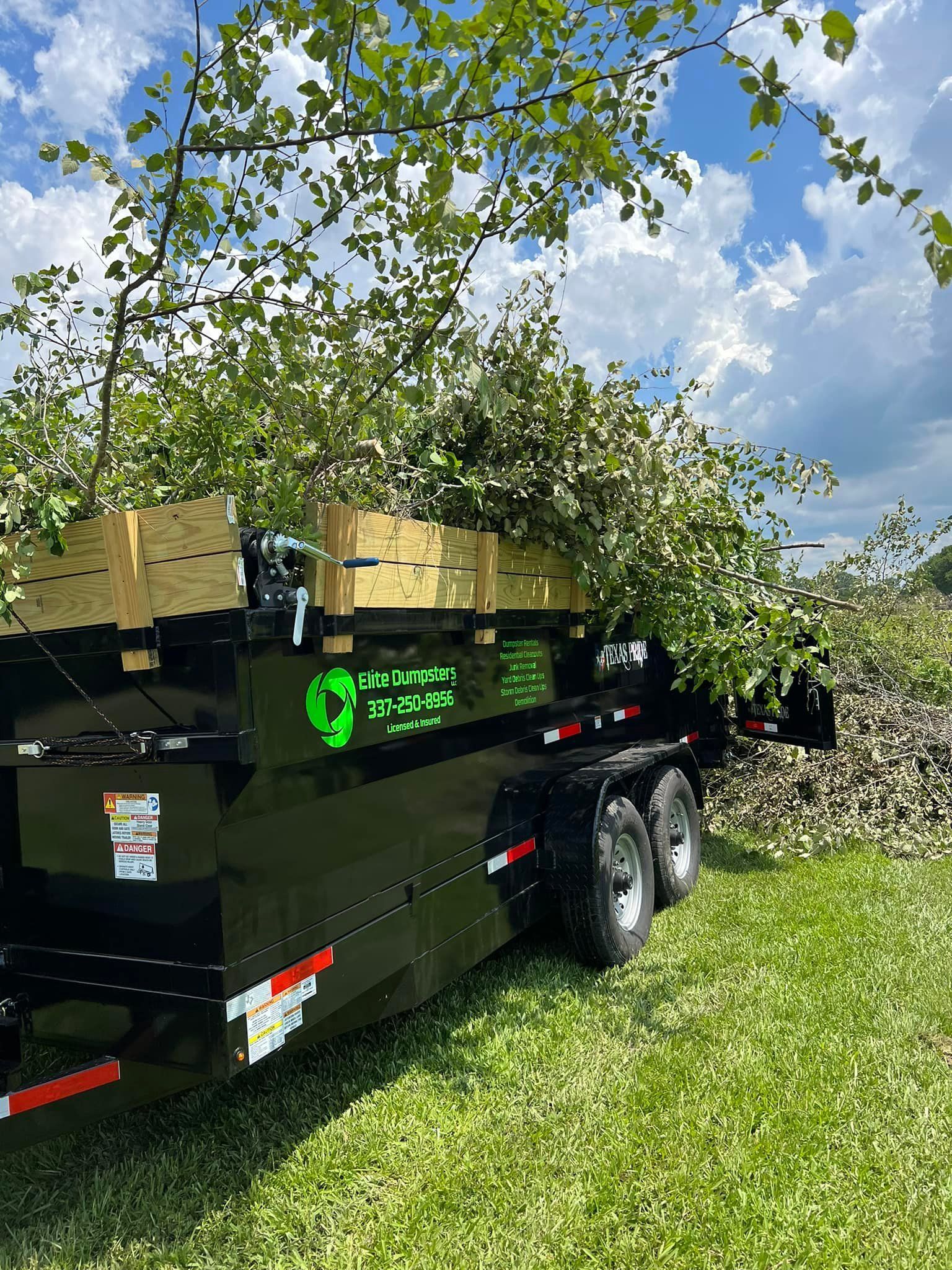 A dumpster is sitting on top of a lush green field.
