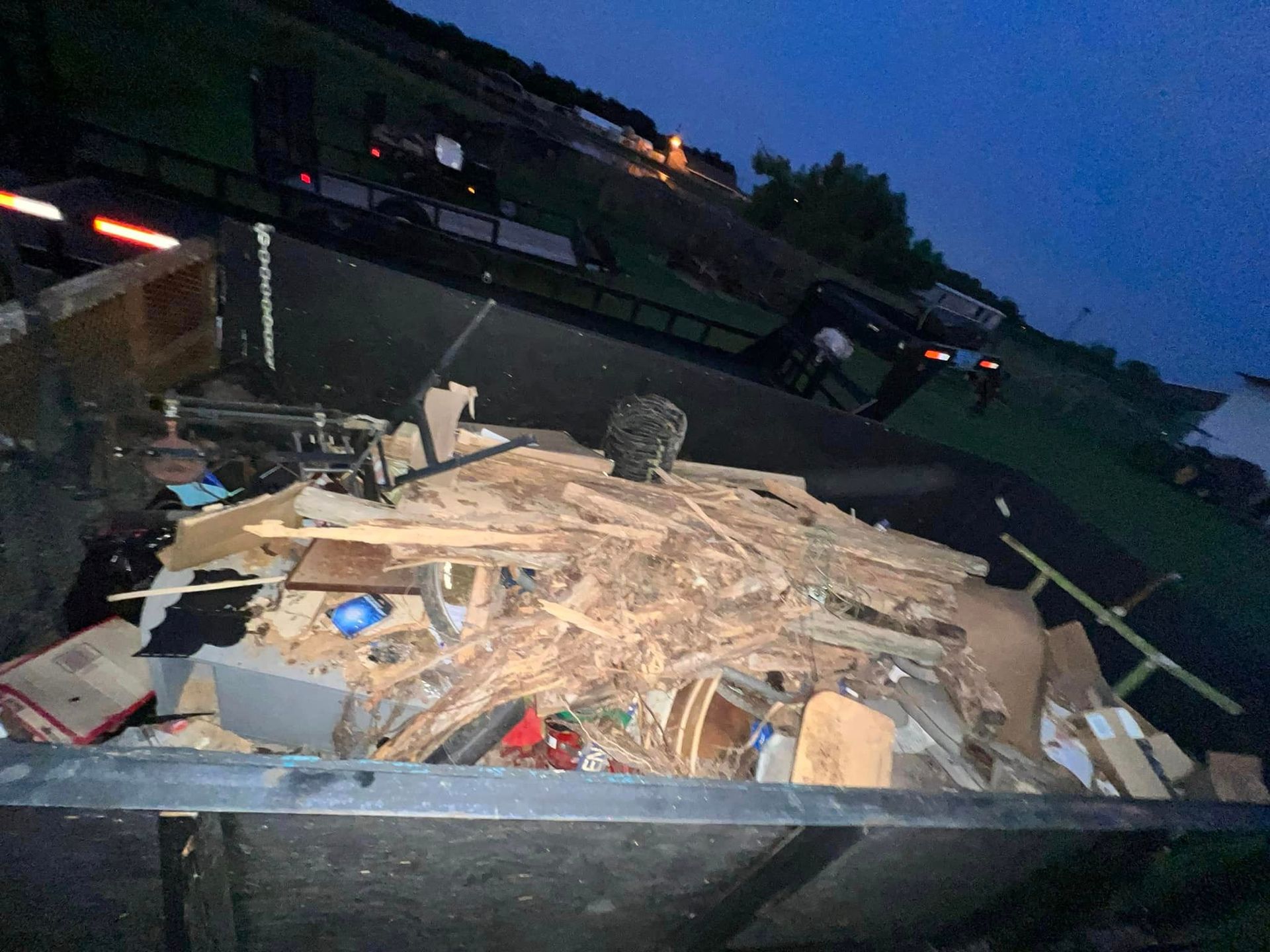 A dumpster filled with junk is sitting on the side of the road.