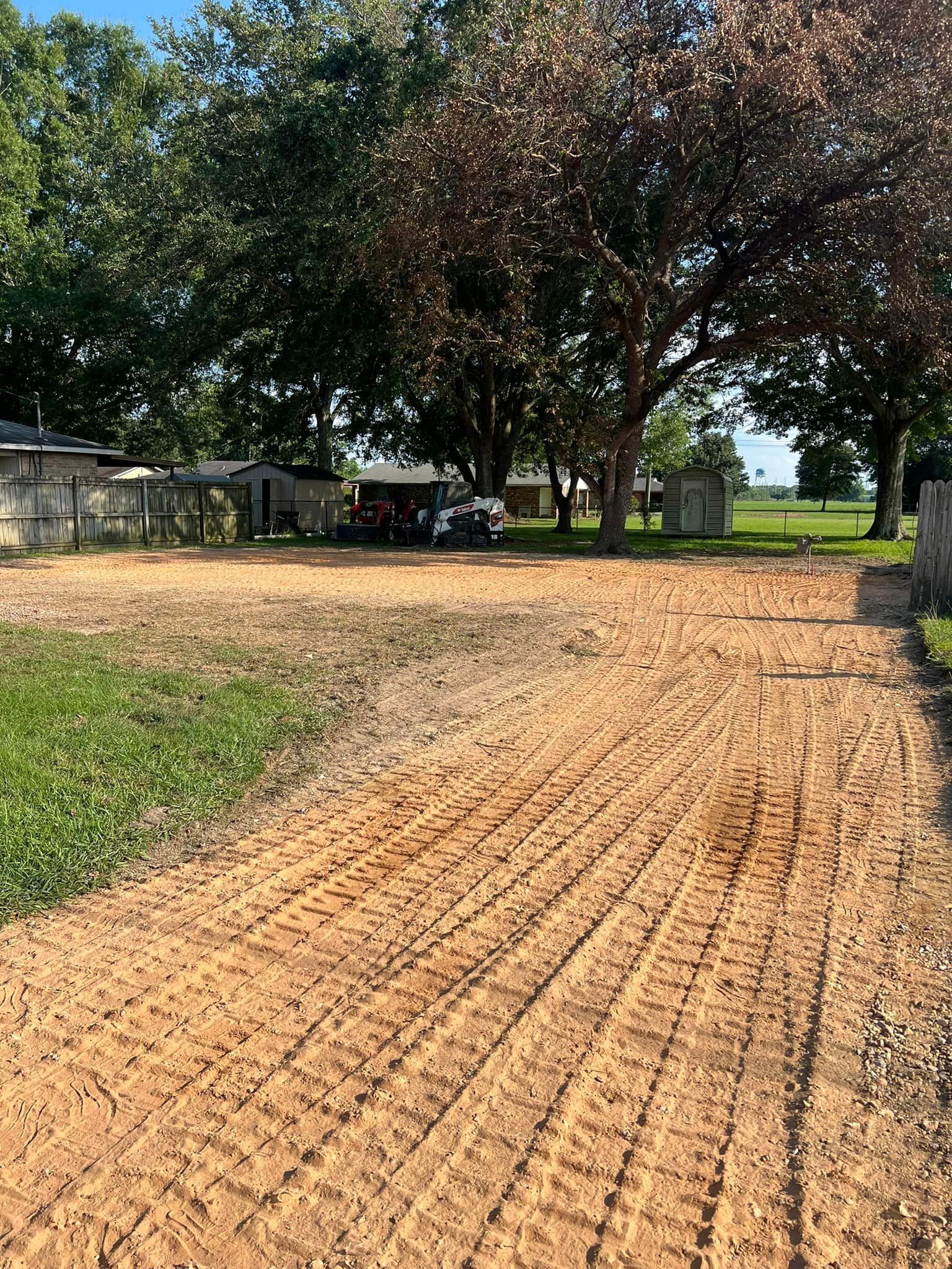 A dirt road leading to a house with trees in the background.