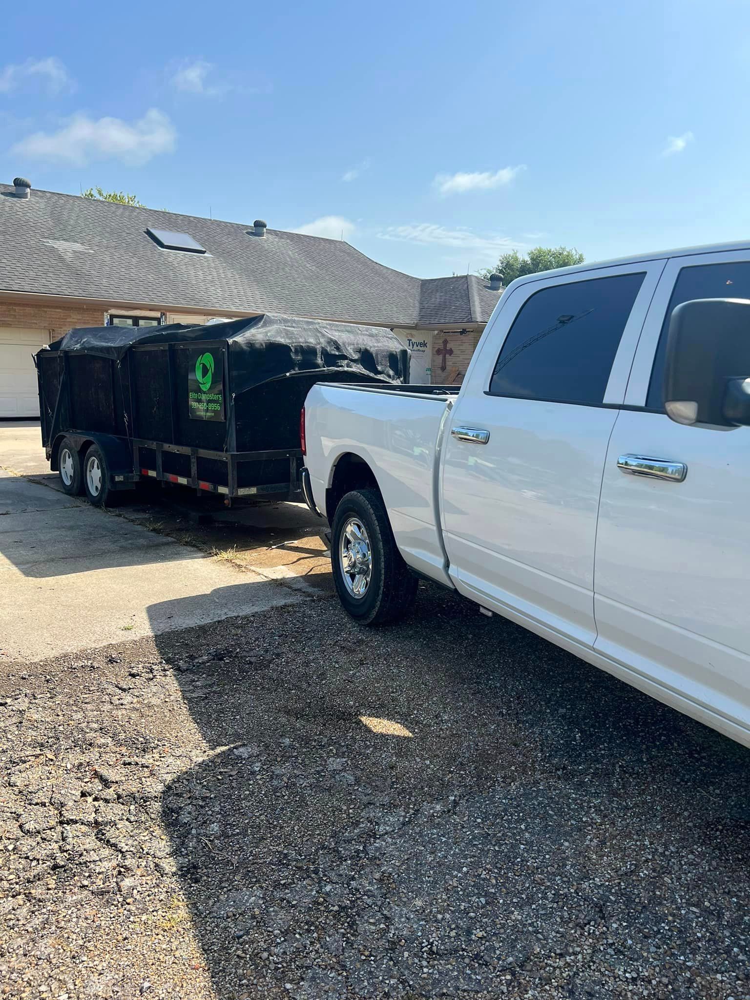 A white truck is parked next to a black trailer.