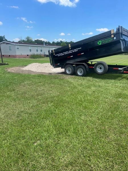 A dumpster is sitting on top of a trailer in a grassy field.
