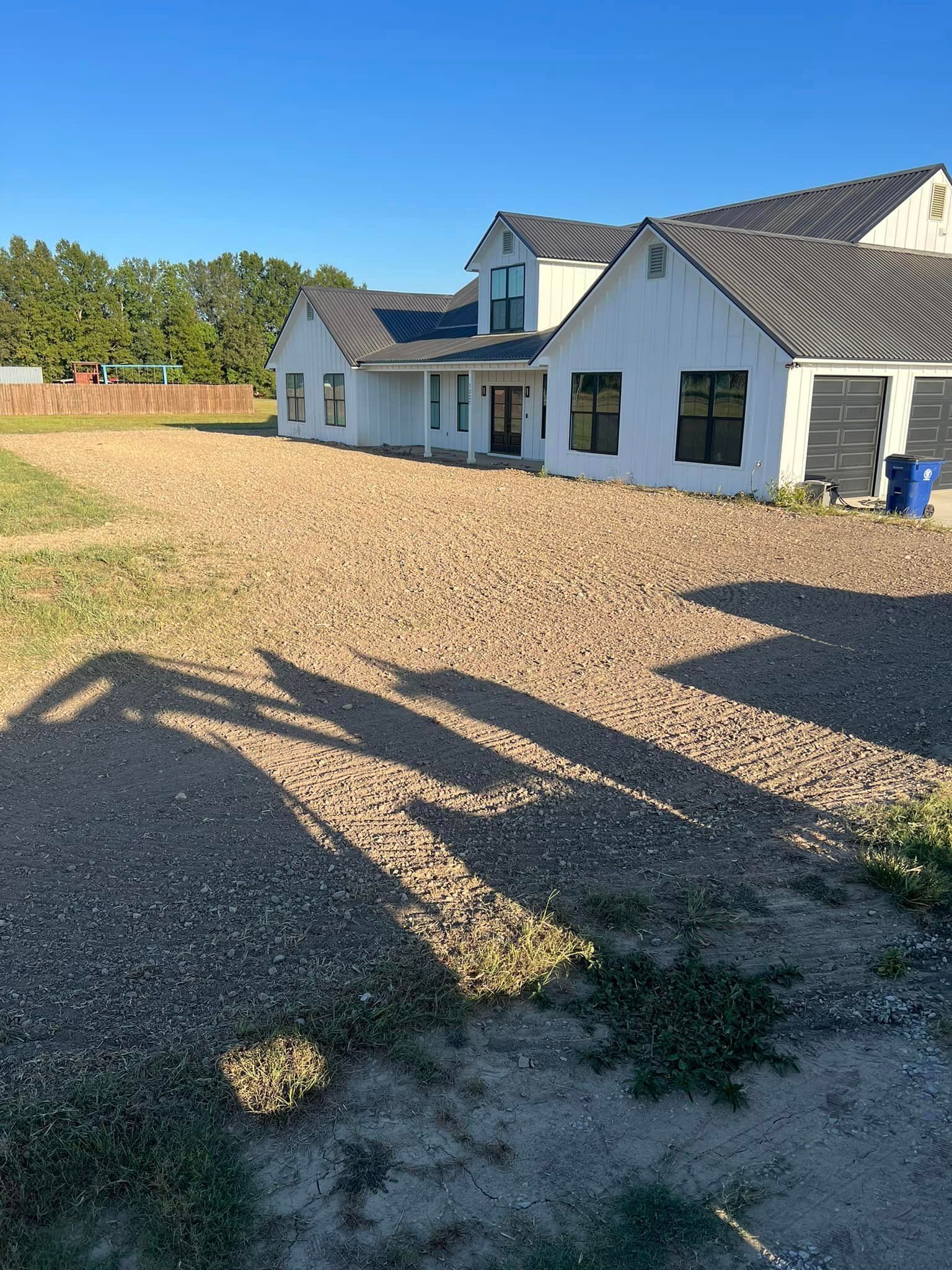 A large white house with a gravel driveway in front of it.