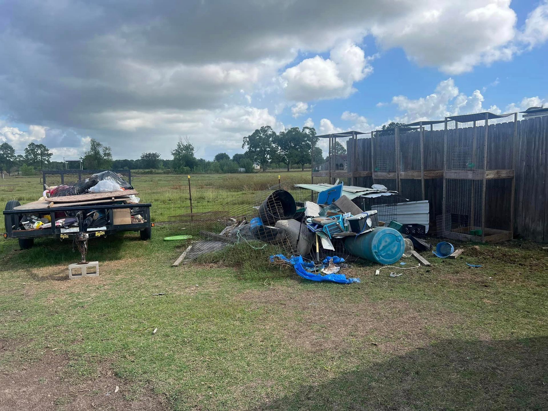 A trailer is parked in a grassy field next to a fence.