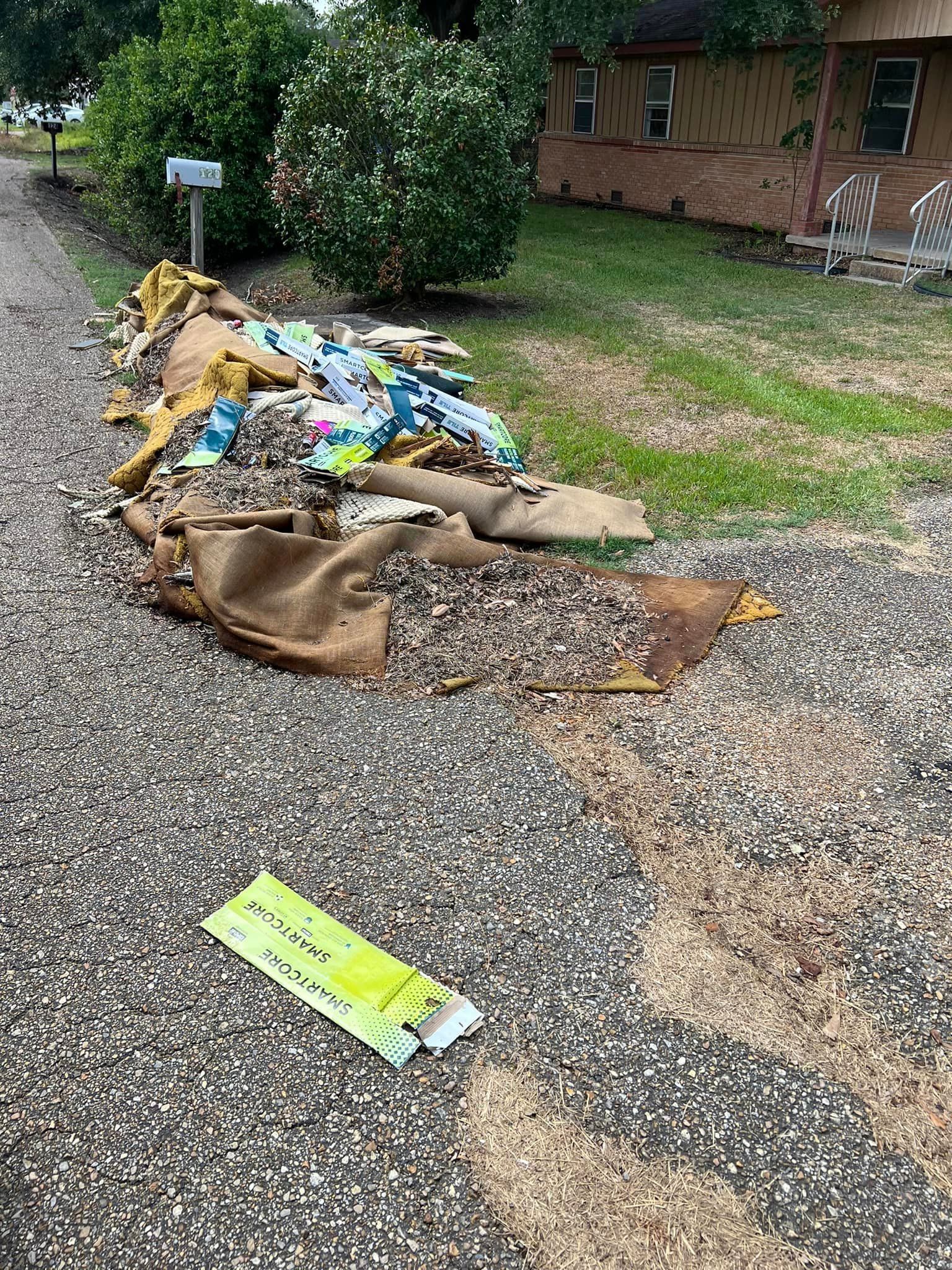 A pile of trash is sitting on the side of the road in front of a house.