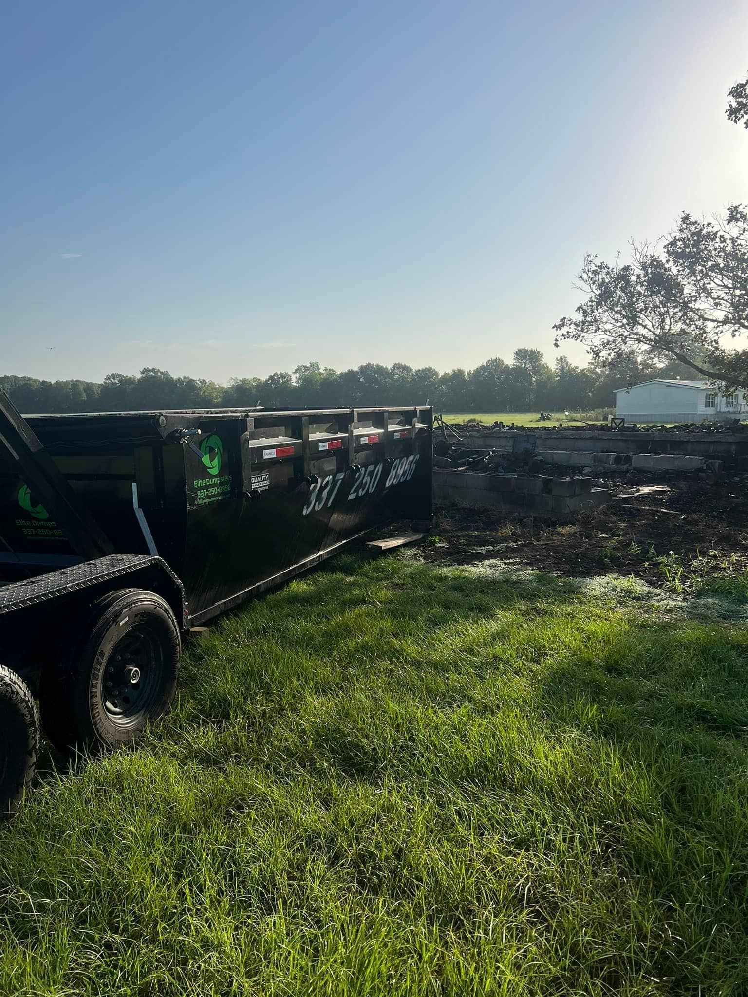 A black trailer is parked in a grassy field.