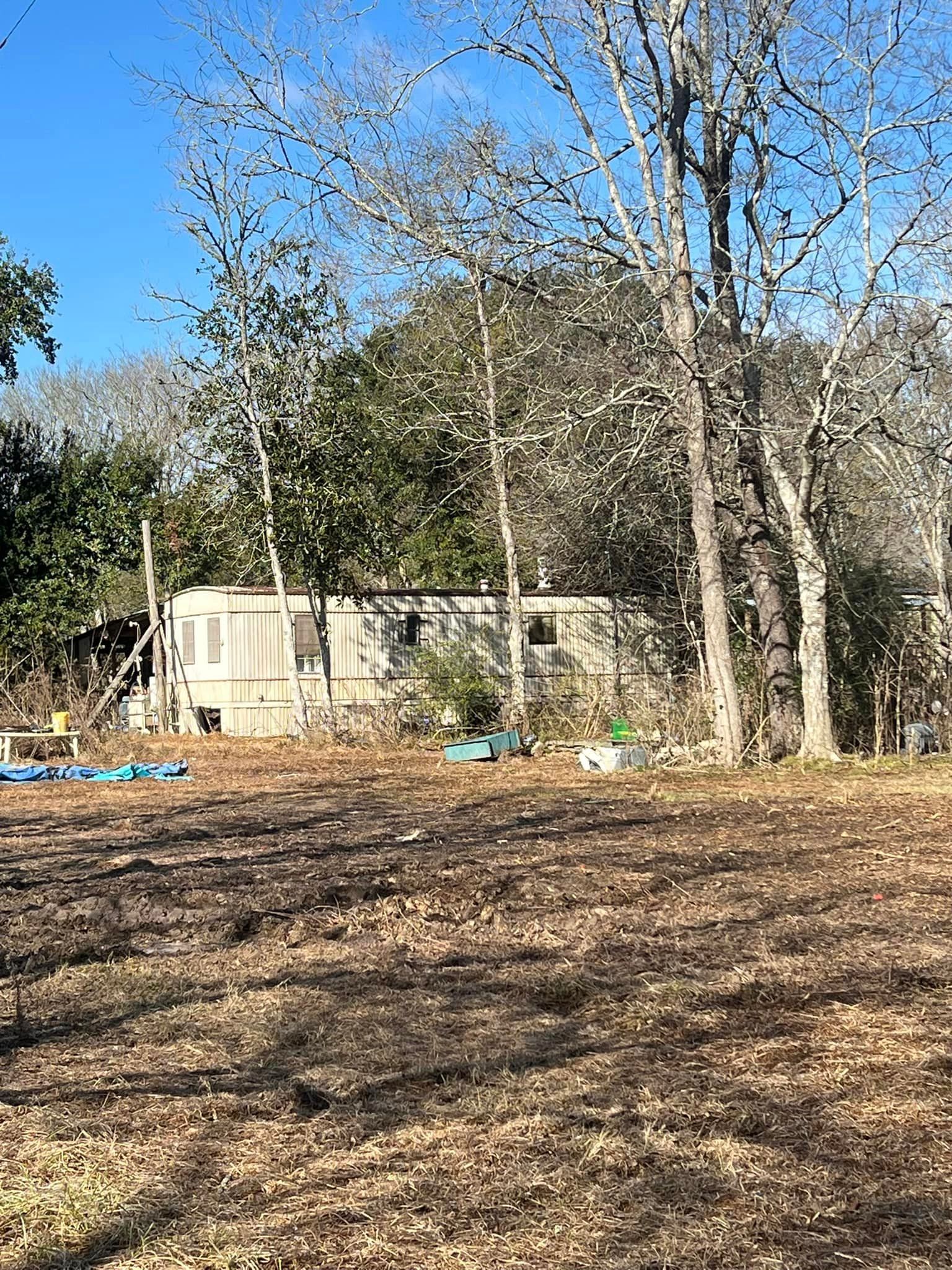 A trailer is parked in the middle of a field surrounded by trees.