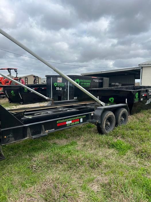 A dumpster trailer is parked in a grassy field.