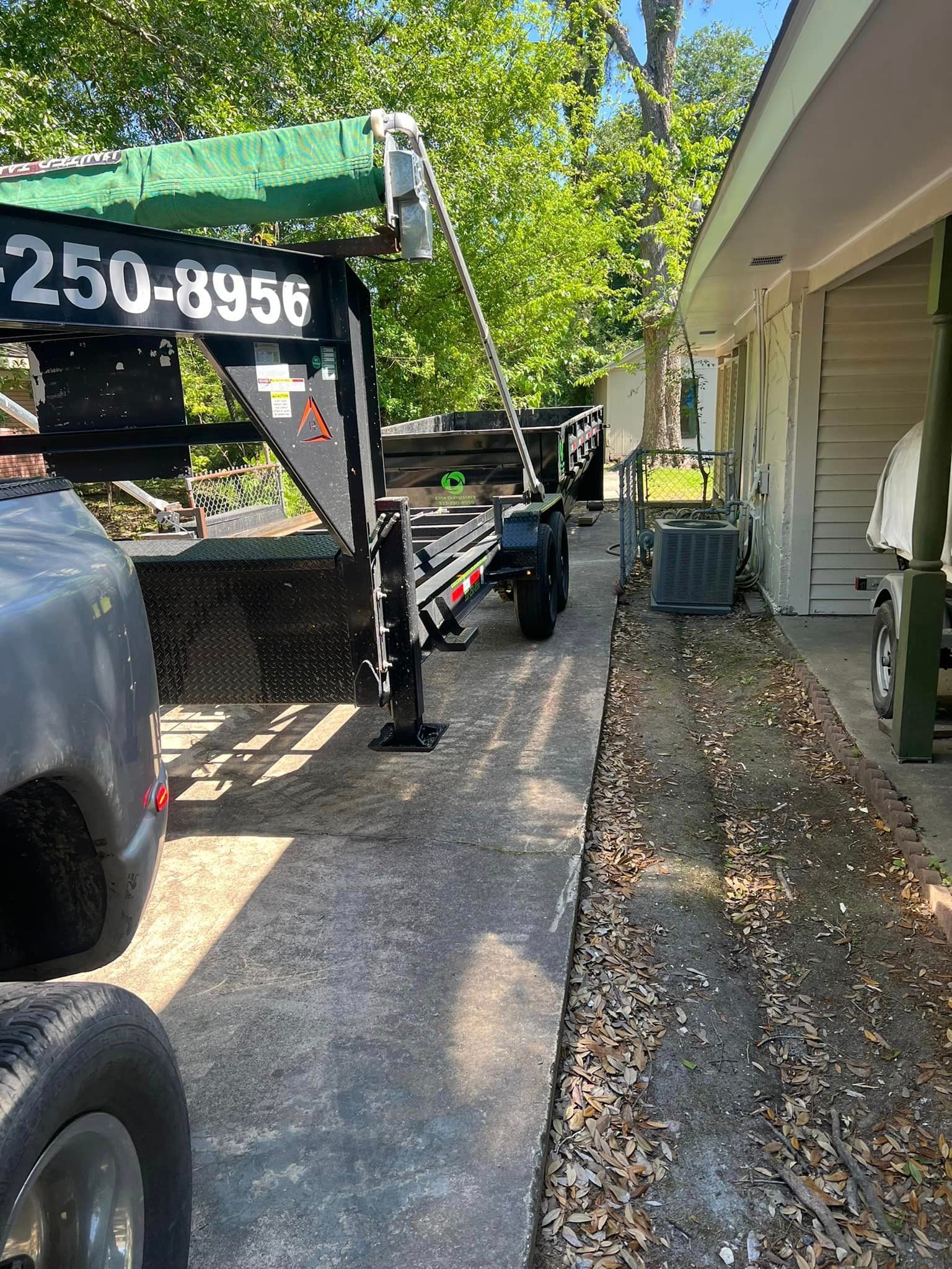 A trailer with a crane attached to it is parked in front of a house.