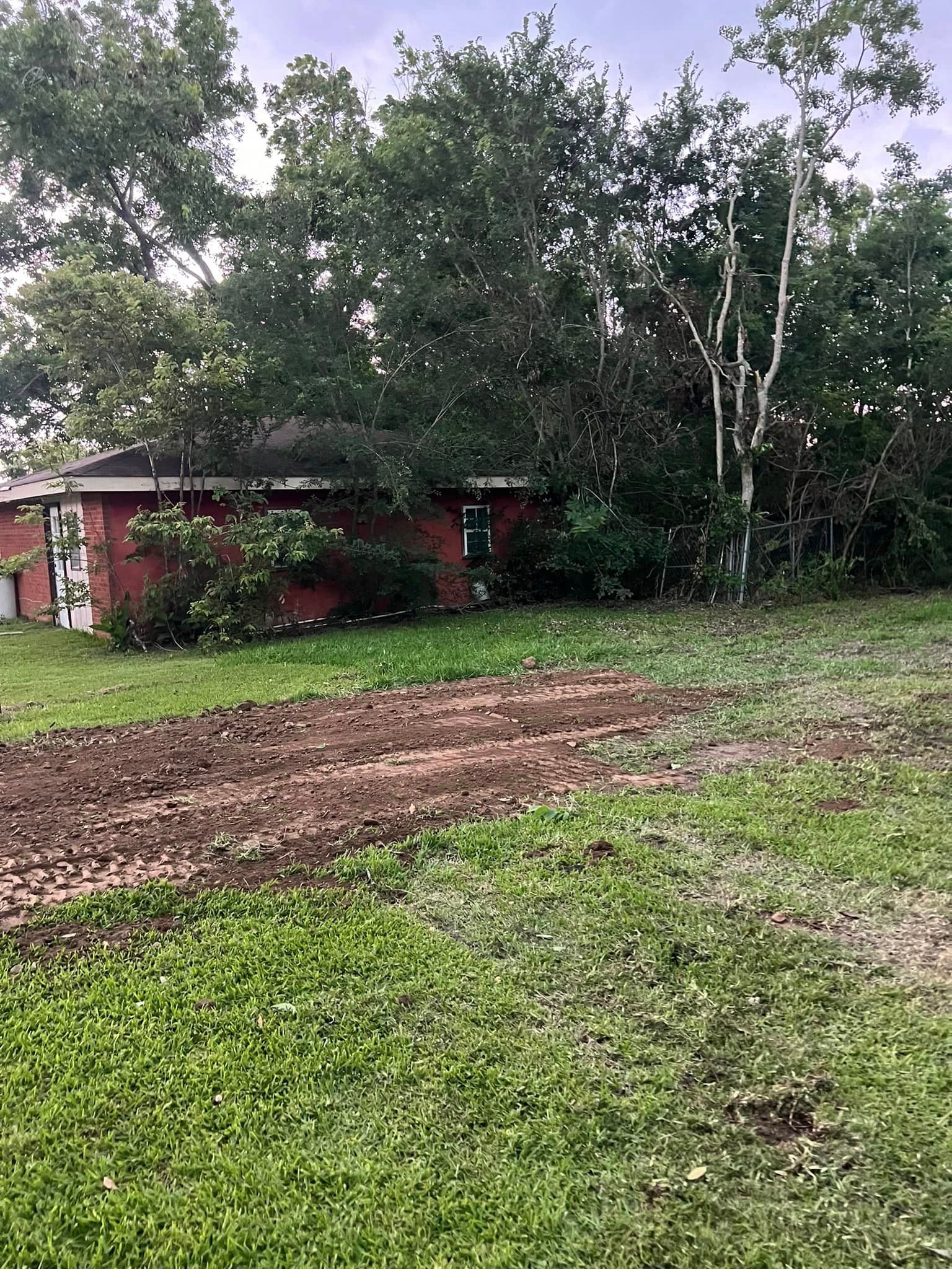 A house is sitting in the middle of a lush green field surrounded by trees.