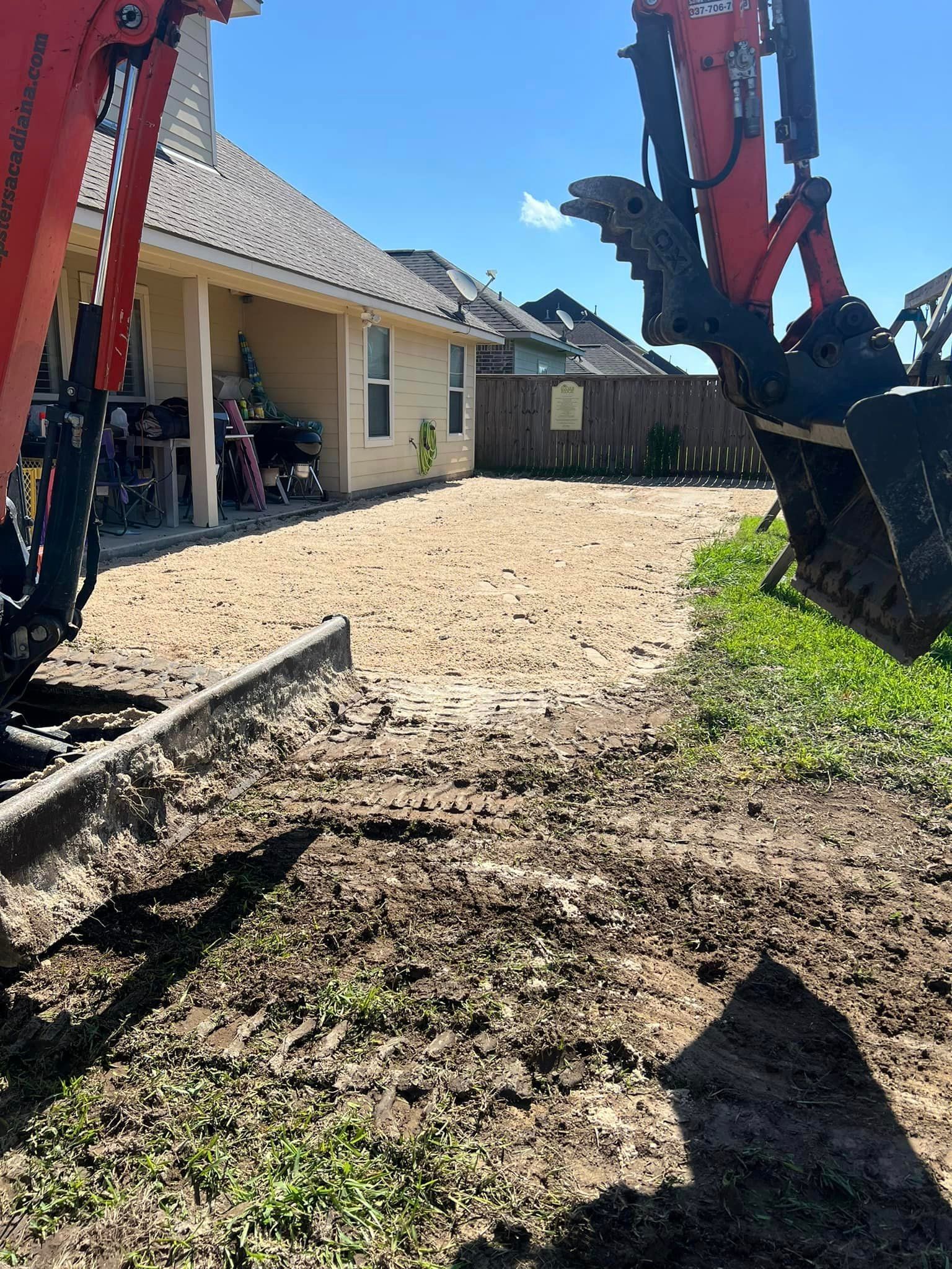 An excavator is digging a hole in the dirt in front of a house.