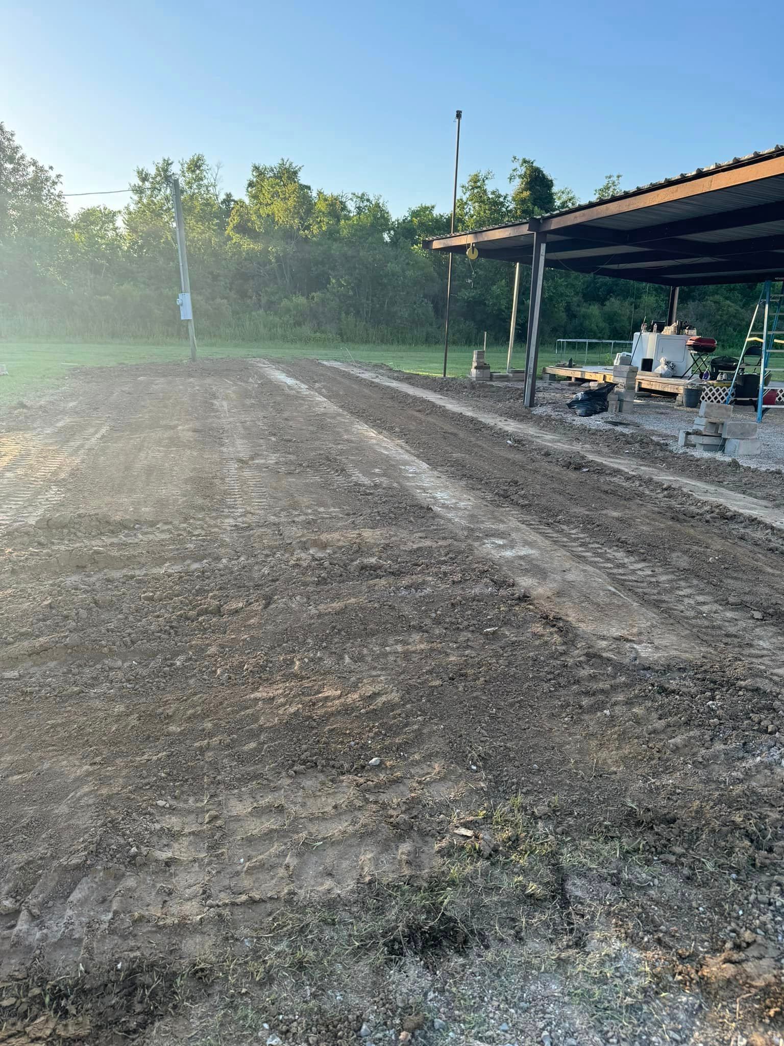 A dirt field with a covered area in the background.