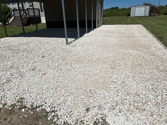 A gravel driveway with a shed in the background