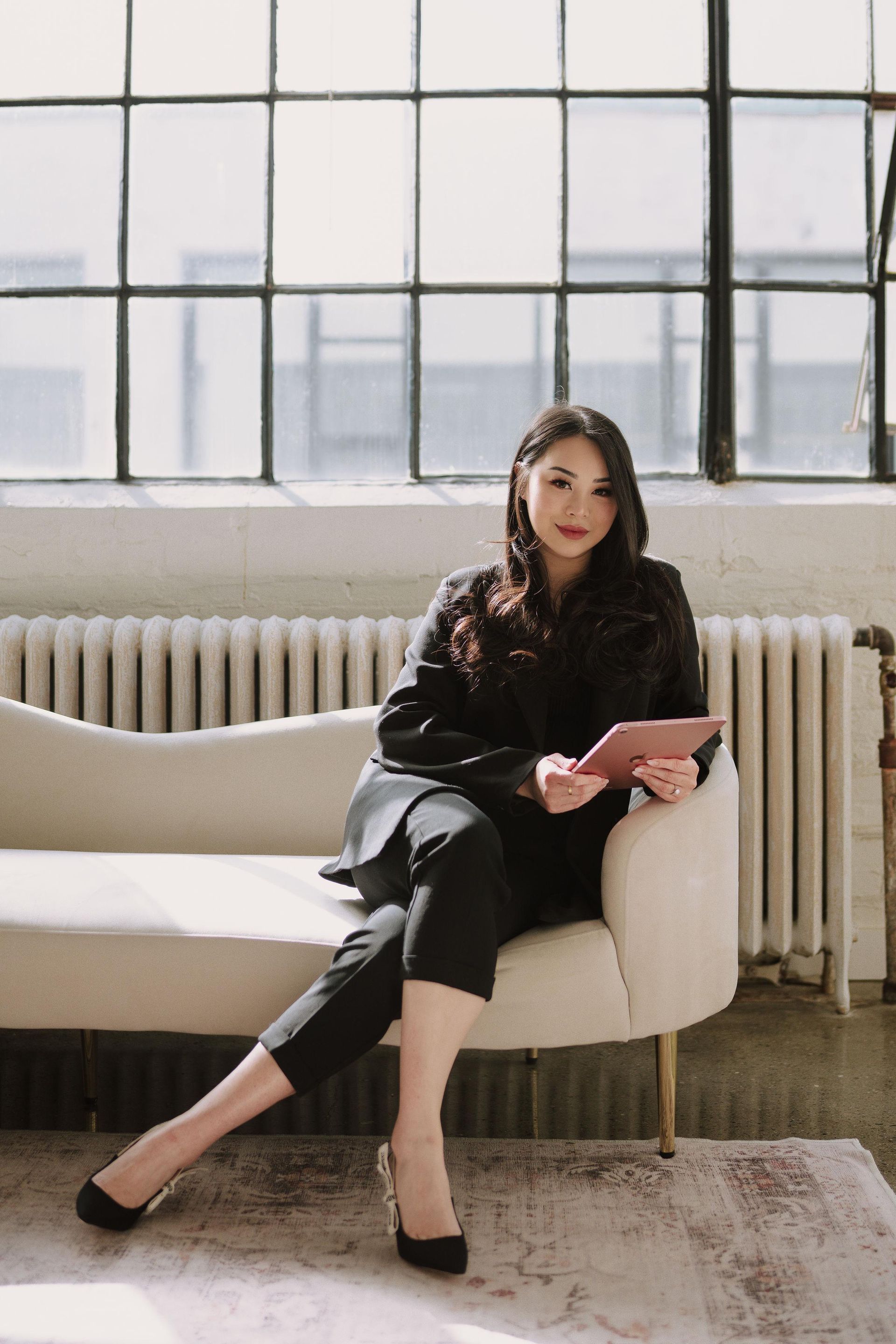 a woman is sitting on a couch holding a bottle of perfume .