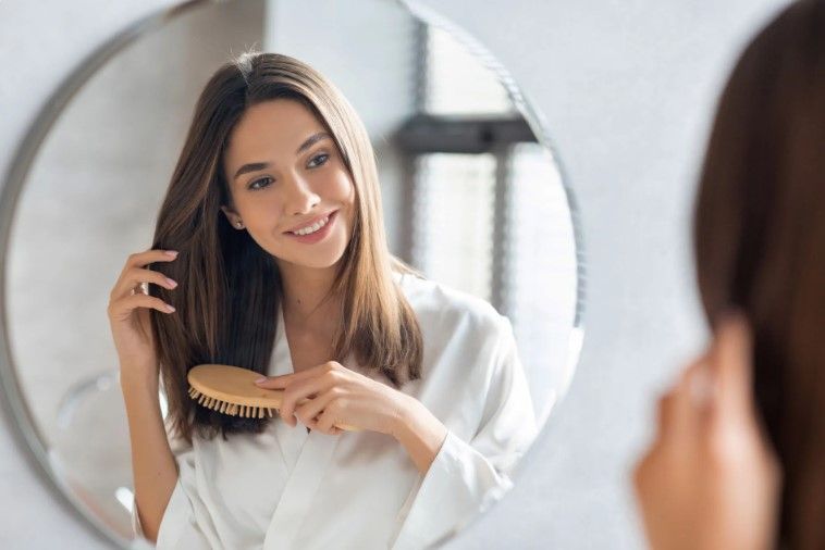 a woman is brushing her hair in front of a mirror .