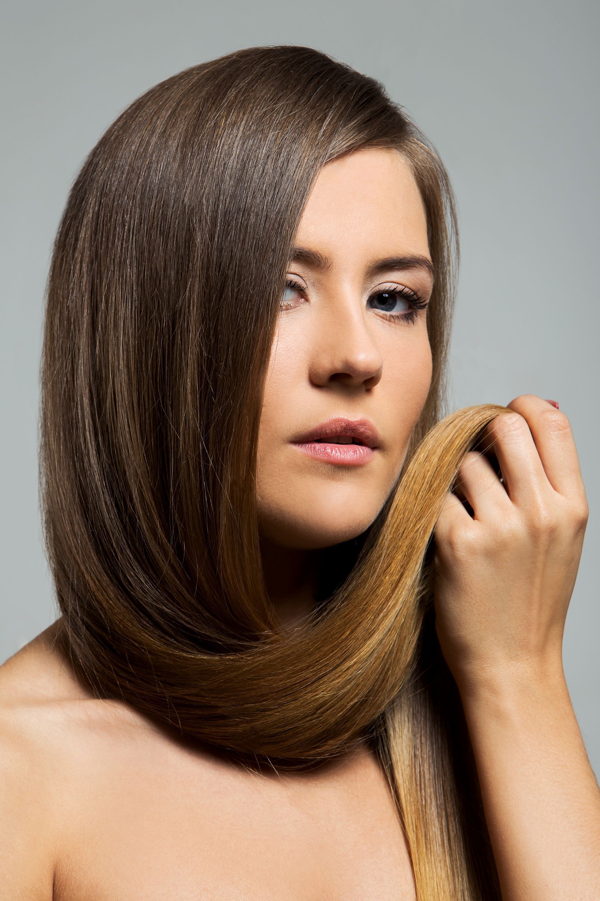 A woman with long hair is holding her hair in her hands.