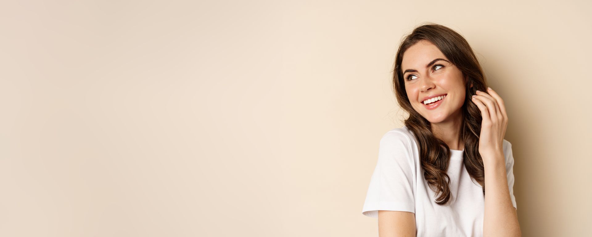 A woman in a white t-shirt is smiling and looking up.