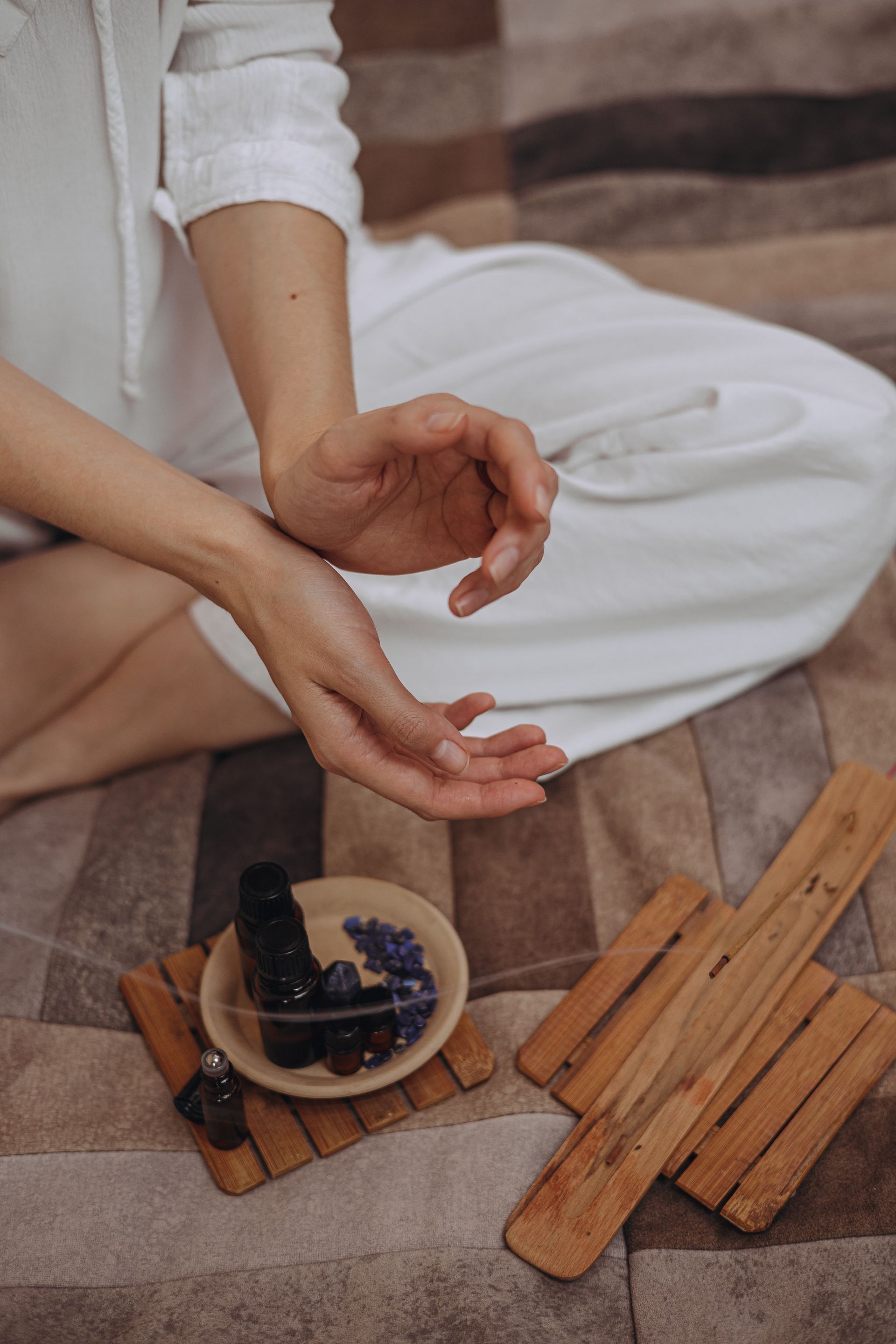 A woman is sitting on the floor with her hands on her wrist.