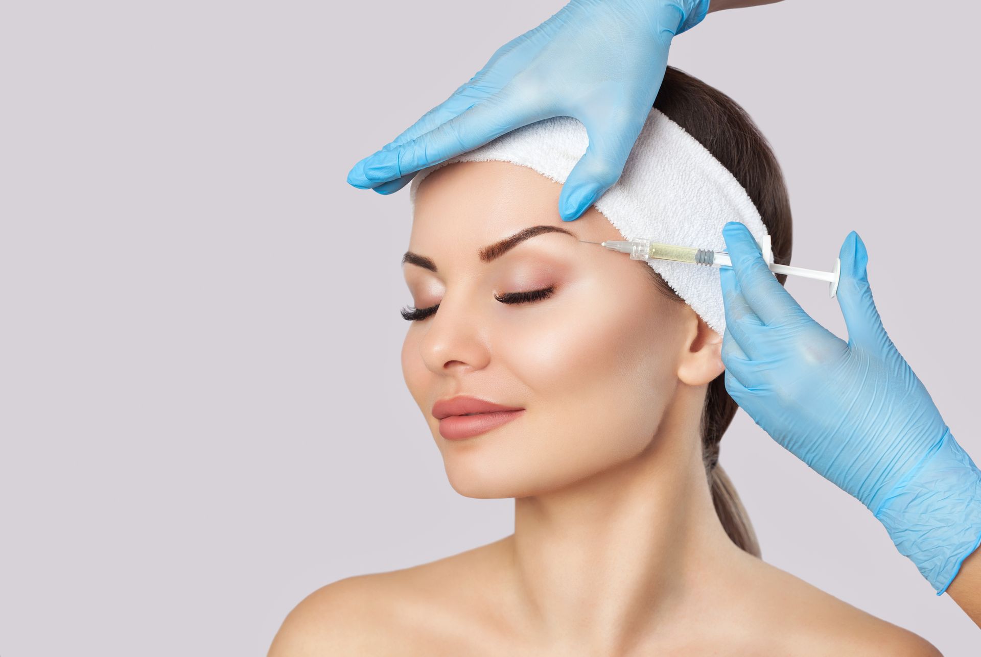 a woman is getting a botox injection in her forehead .