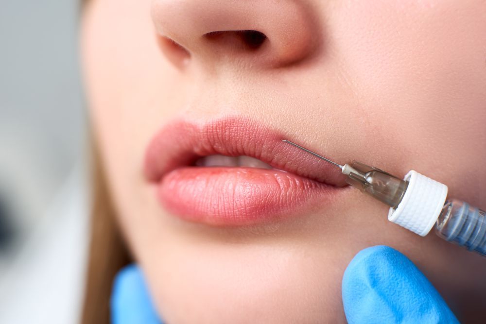 A woman is getting a permanent lip tattoo on her lips.