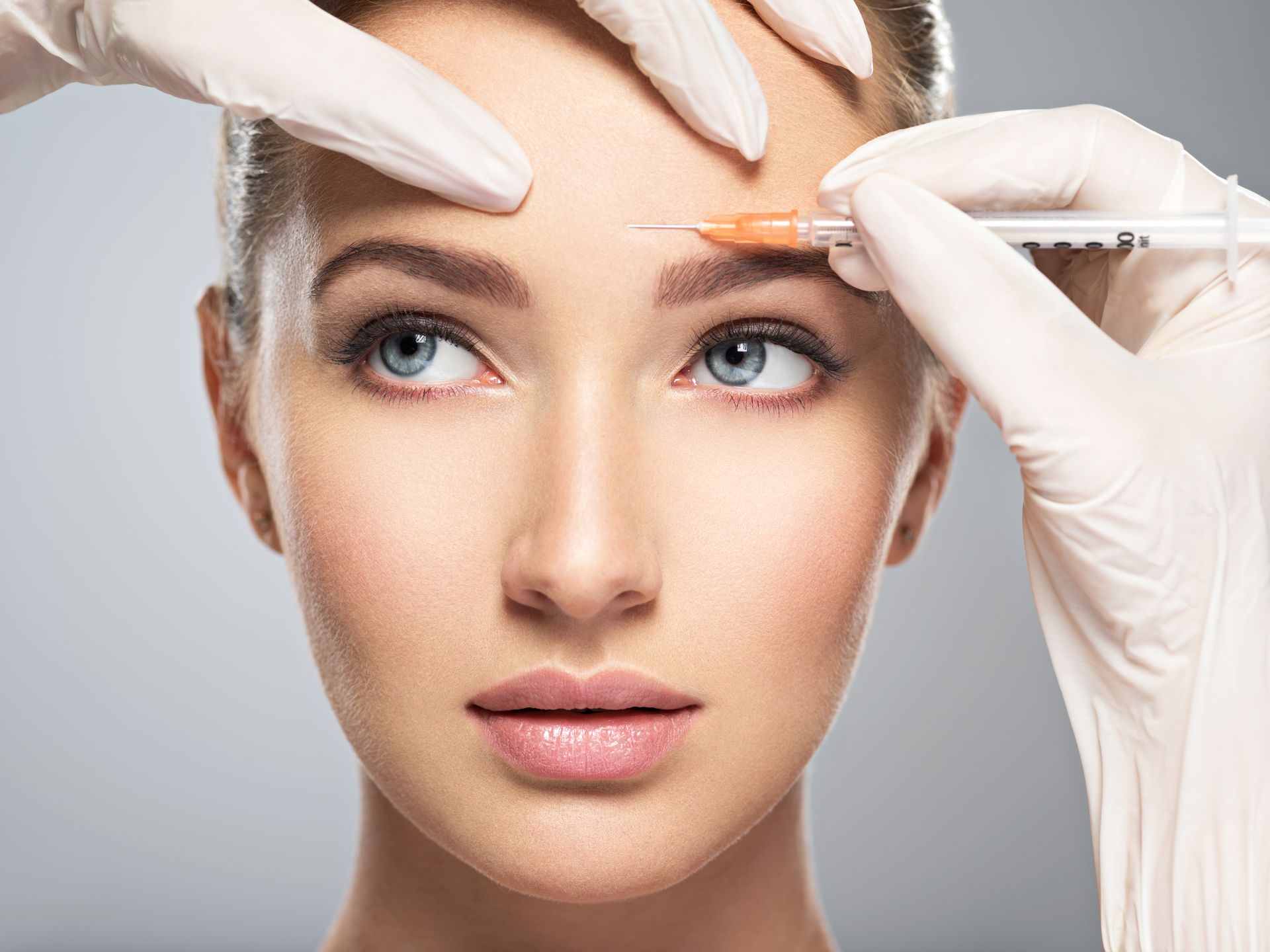 a woman is getting a botox injection on her forehead .