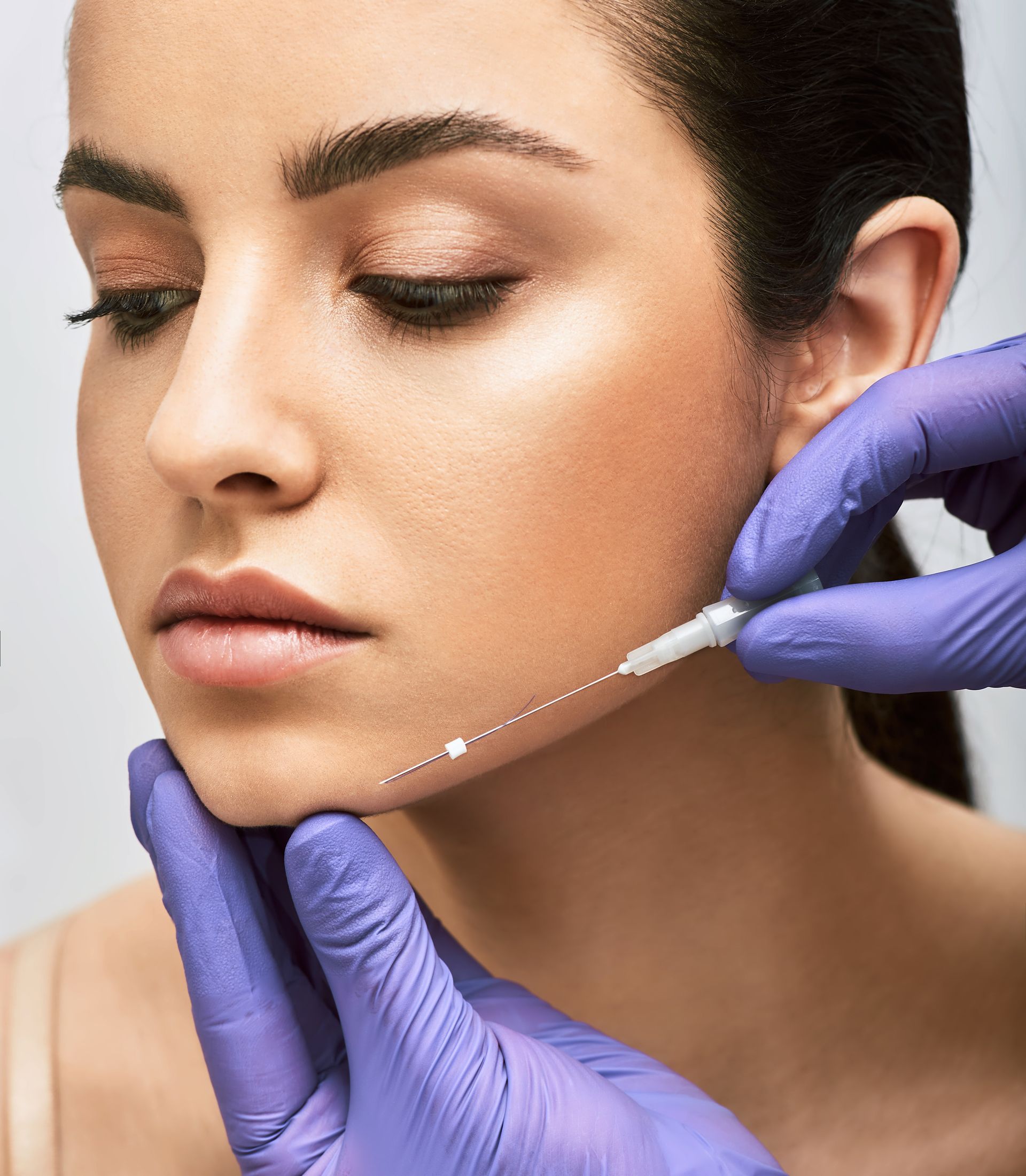 A woman is getting a botox injection in her face.