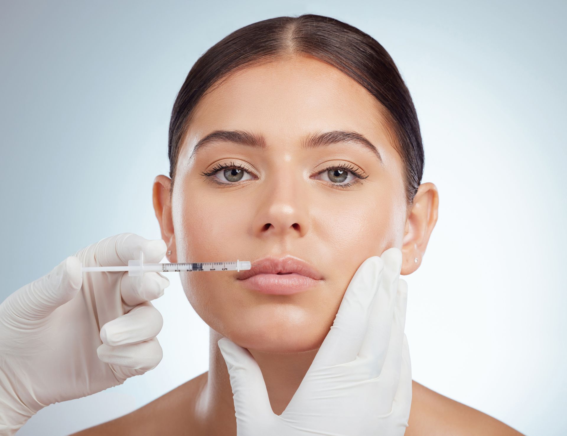 A woman is getting a botox injection in her lips.