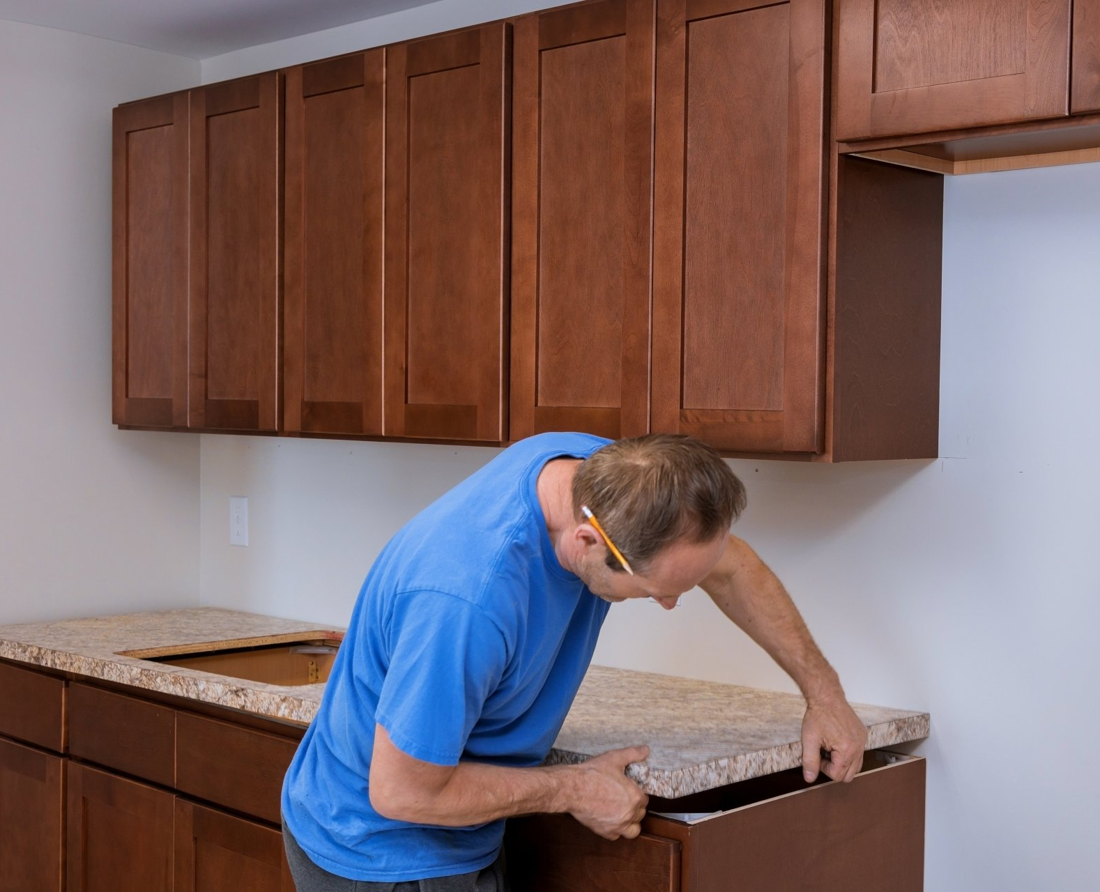 A carpenter installing countertop on a cabinet