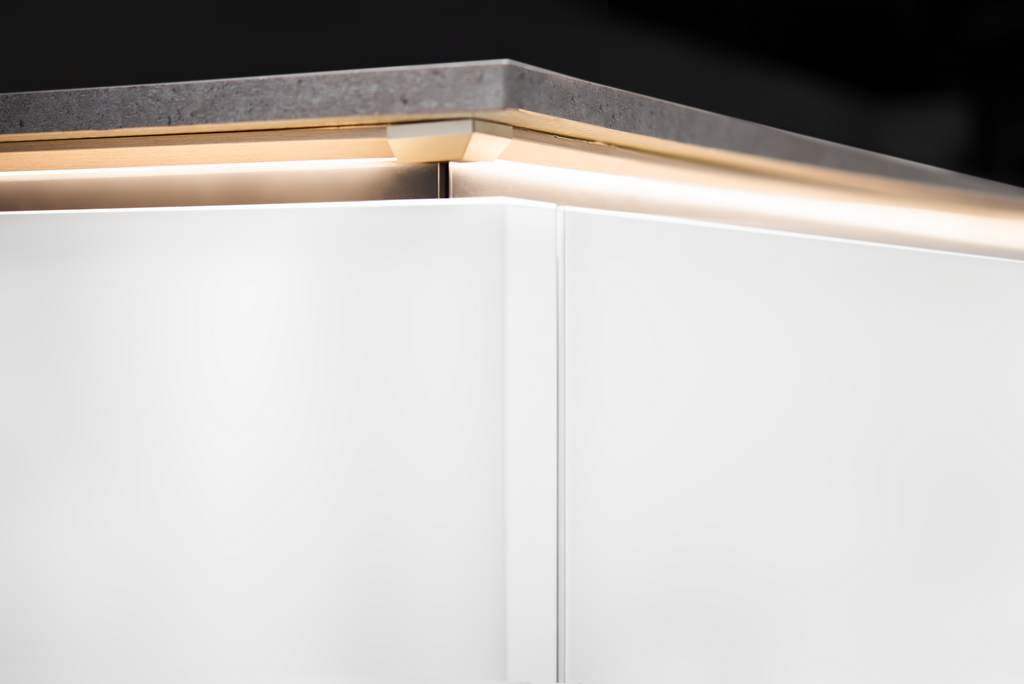White cabinet with a gray countertop and LED lighting illuminating the space below.