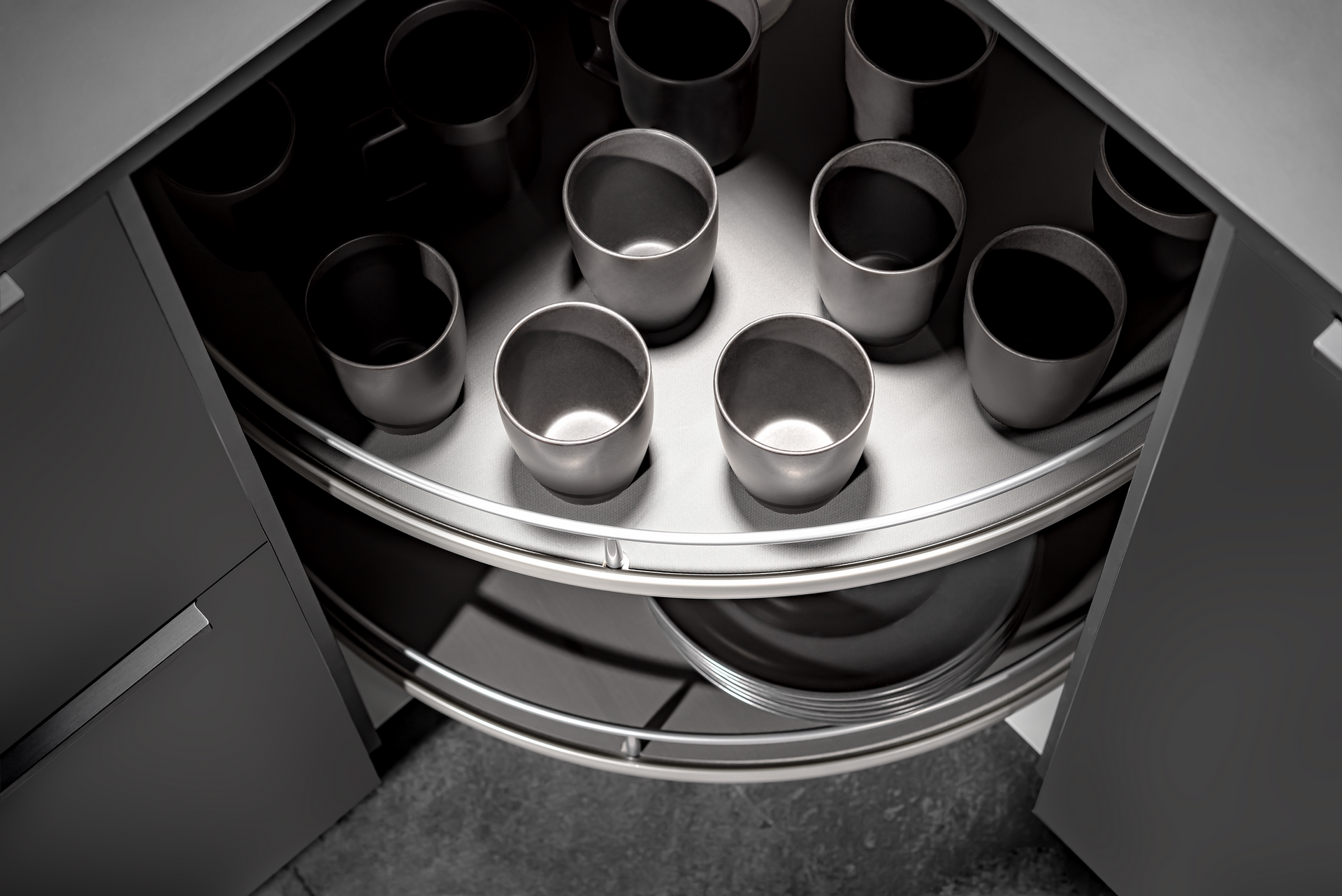 A corner kitchen cabinet with a rotating, semi-circular shelf holding several cups.