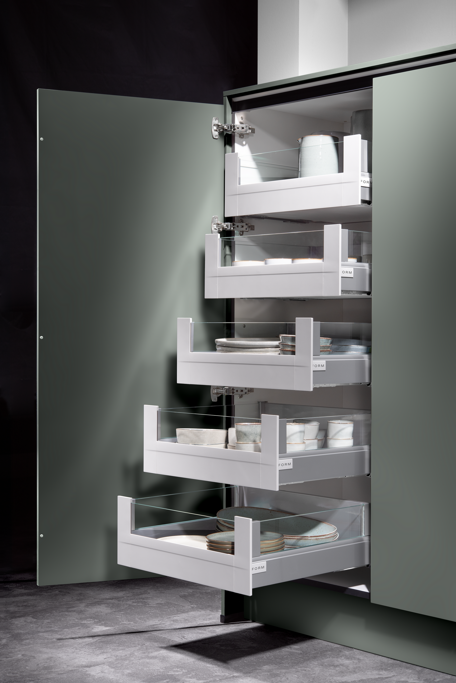 A tall pantry cabinet with a single door open, revealing pull-out drawers filled with kitchen items. The cabinet is gray.