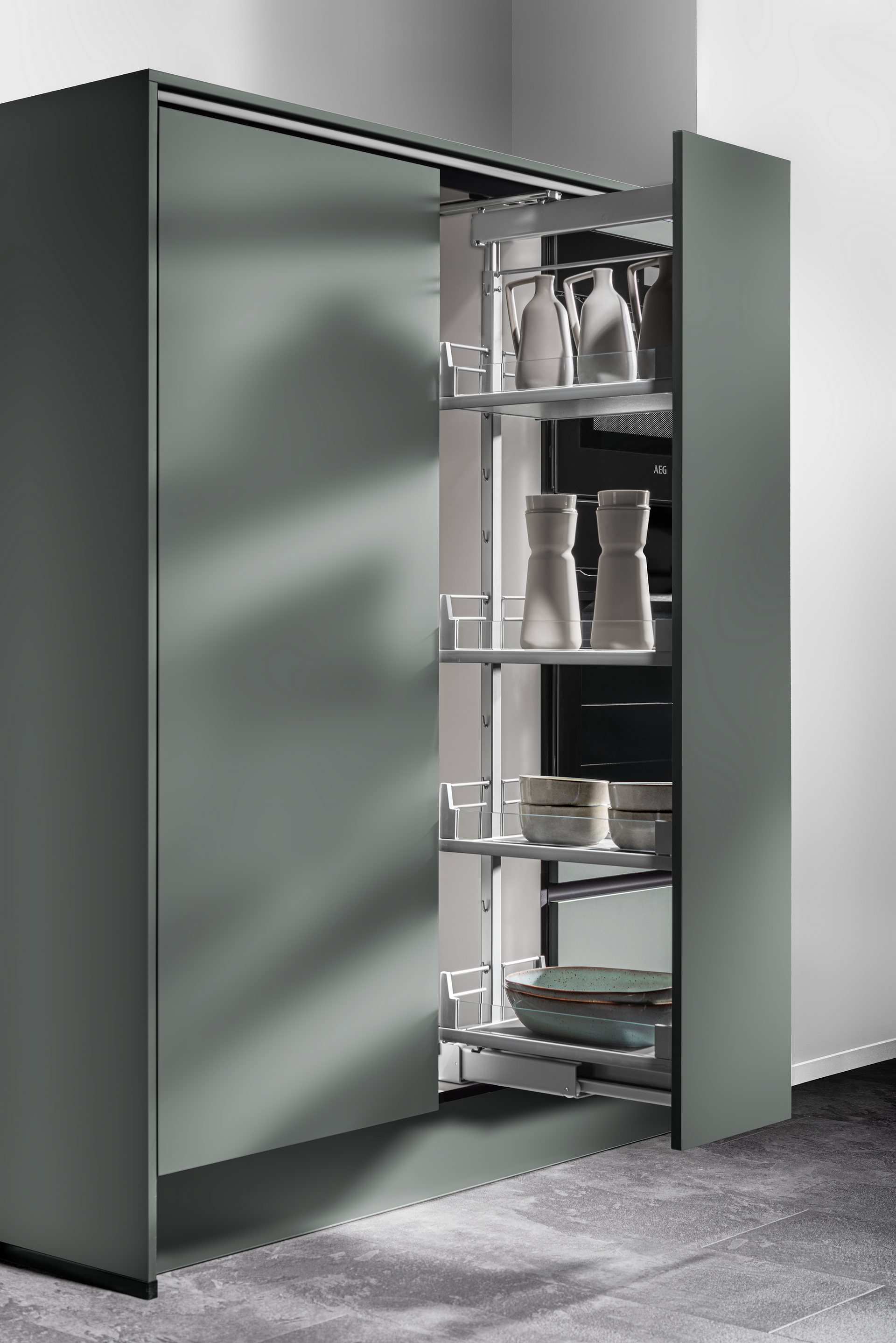 A pull-out pantry cabinet with shelves filled with kitchen items, in a modern gray kitchen setting.