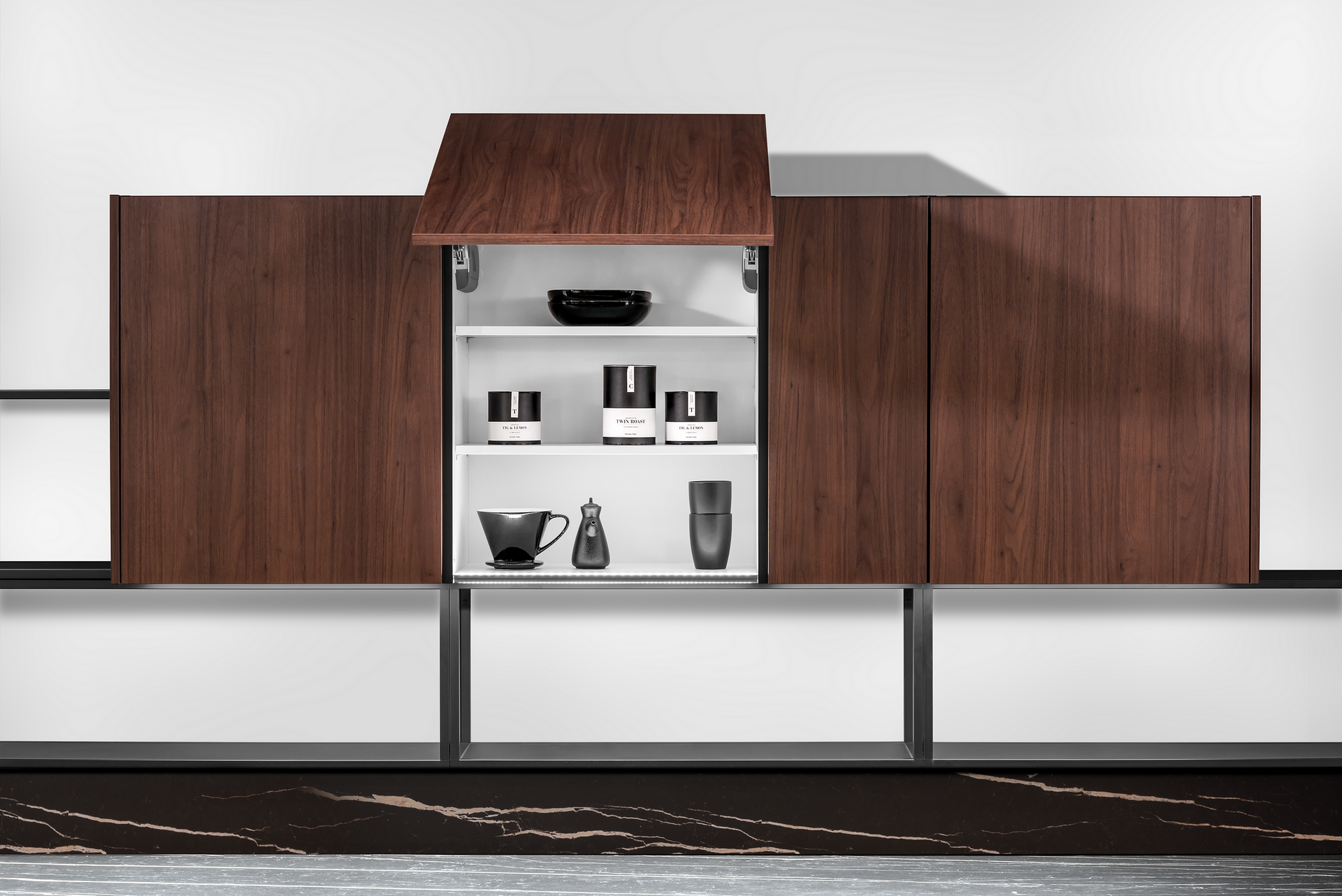 A modern, wall-mounted cabinet with dark wood doors, one open to reveal white shelves and minimalist black containers.