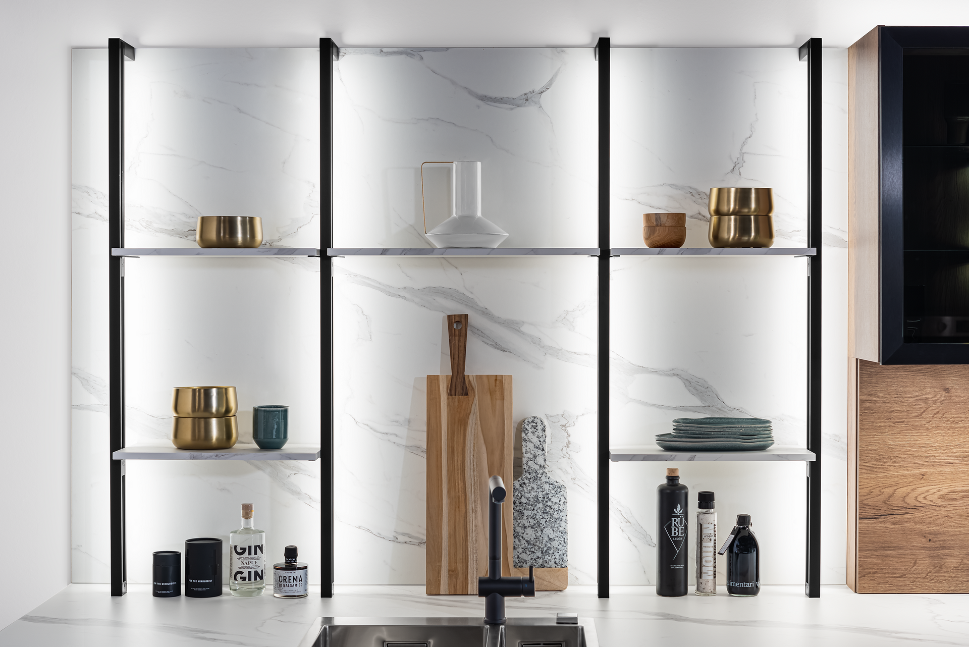 Kitchen shelving unit with marble backsplash, illuminated by LED strips. Shelves display decorative items, including vases, bowls, and bottles.