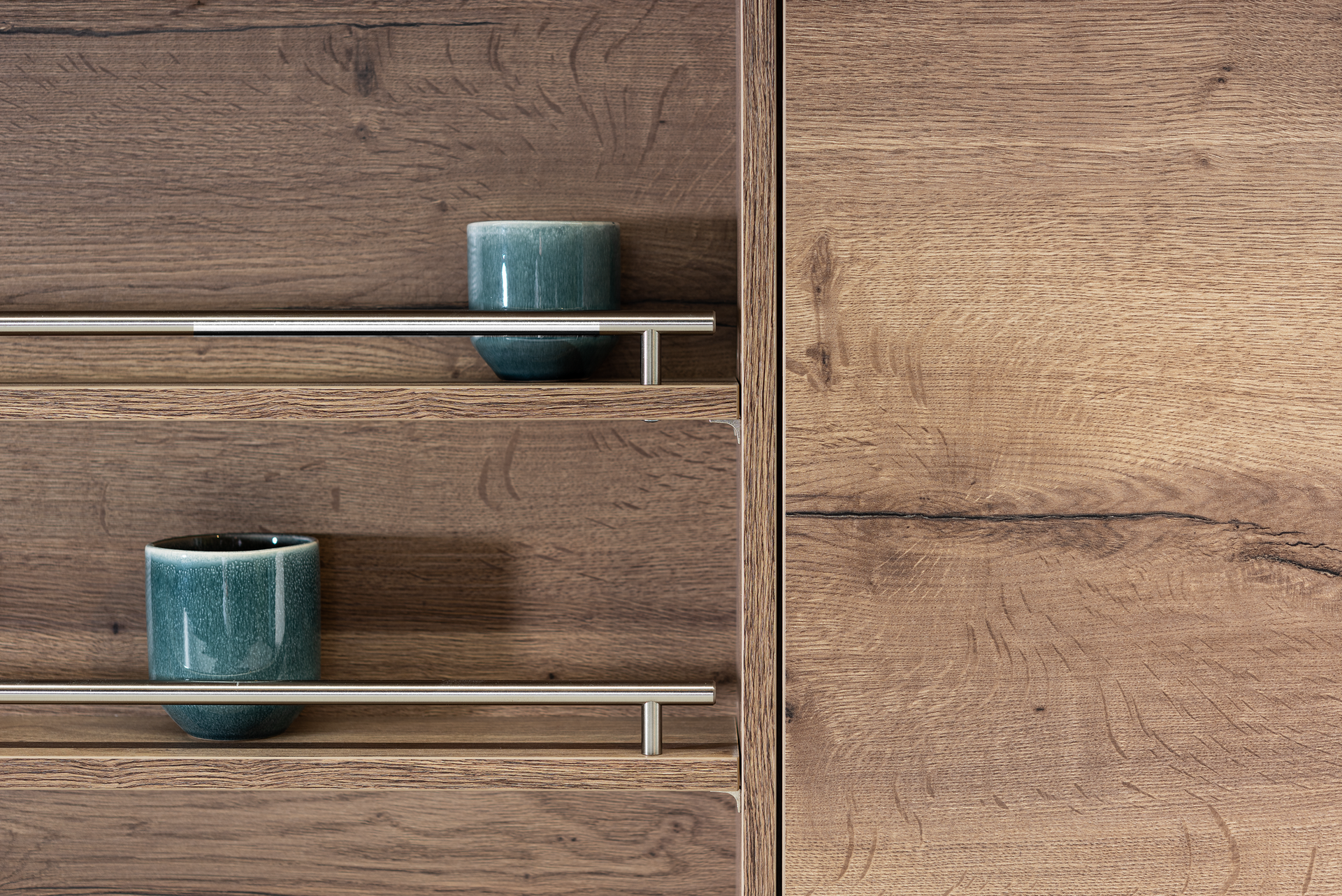 Two teal cups on stainless steel shelves set into a wooden cabinet with a matching wooden door.