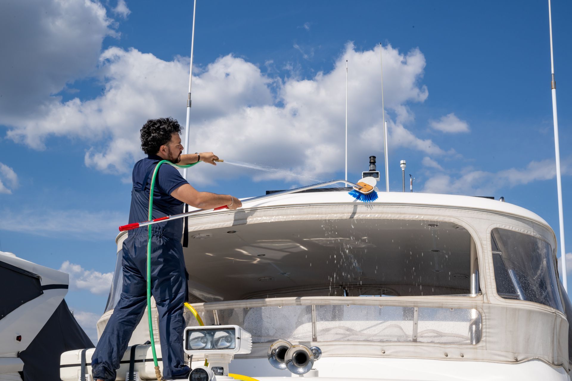 A man is washing a boat with a hose.