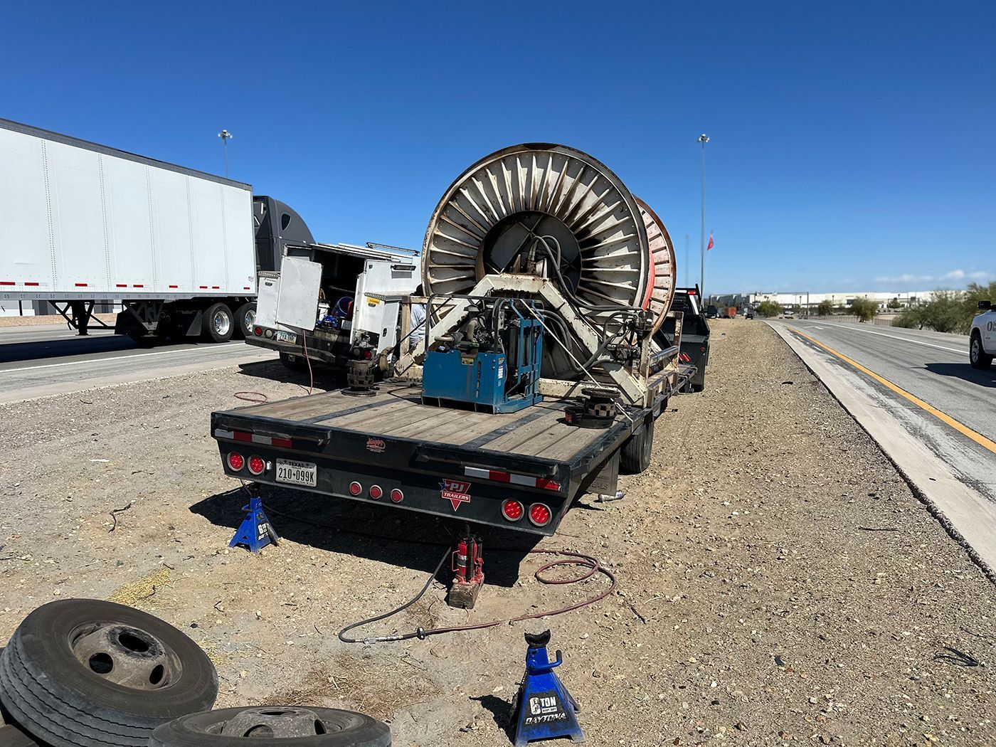 A truck is sitting on the side of the road next to a tire.