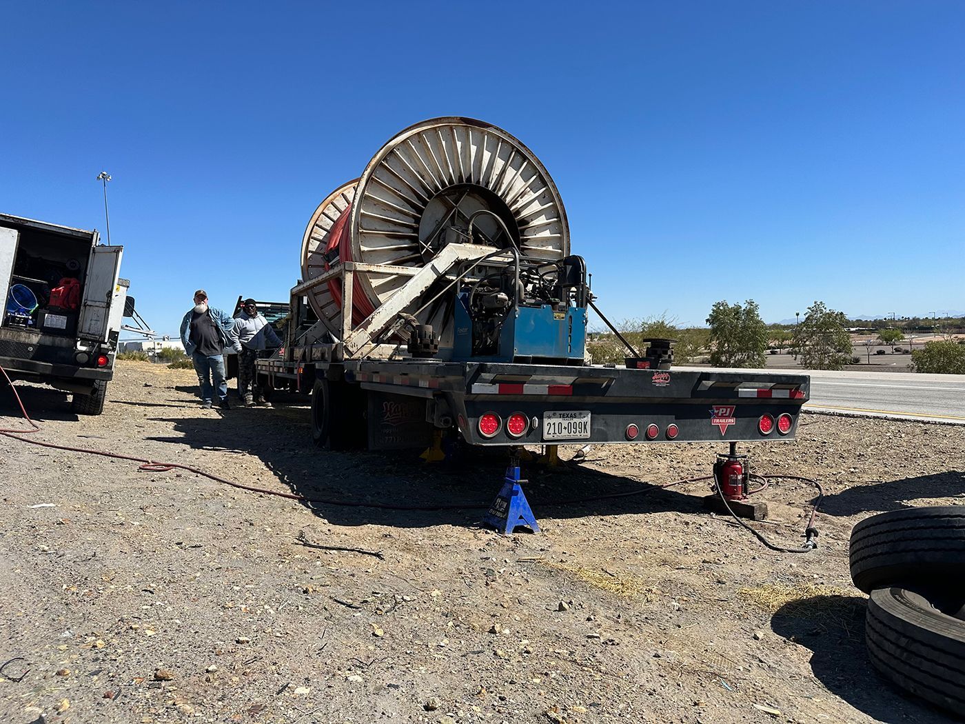A truck with a bunch of wires on it is parked in a gravel lot.