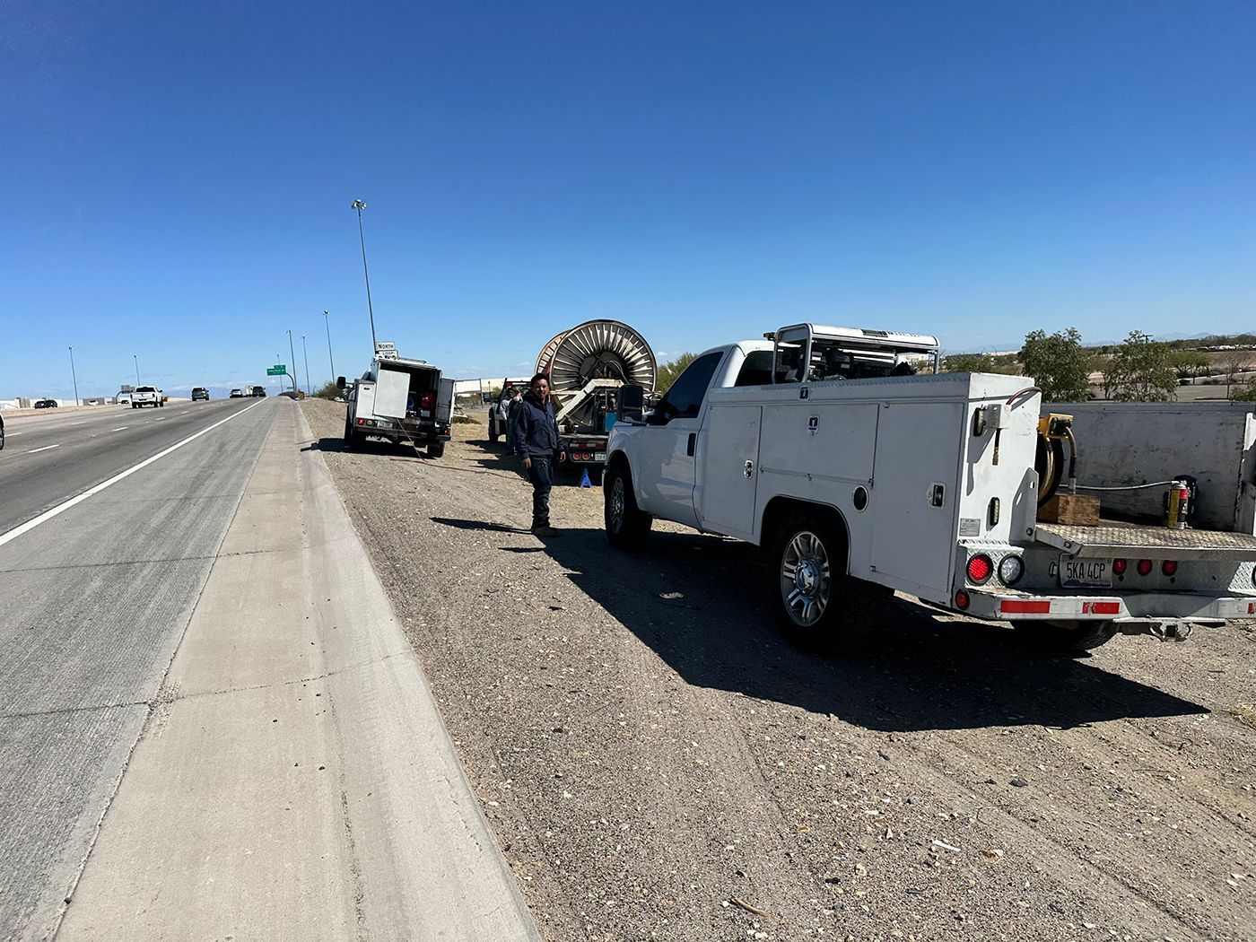 A white truck is parked on the side of a highway.