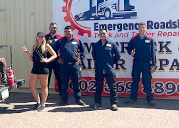 a group of people standing in front of a sign that says emergency roadside truck and trailer repair .